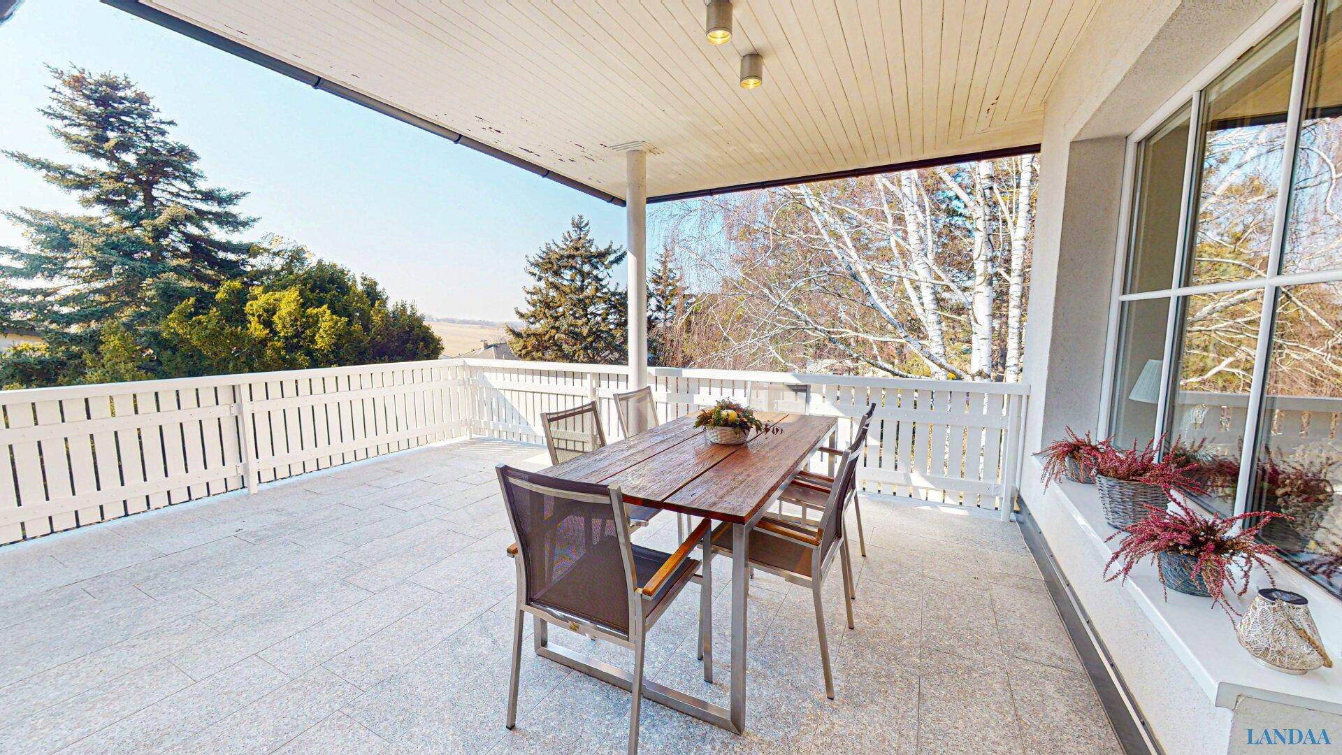 Geräumige Terrasse mit Esstisch und Stühlen, ideal für Mahlzeiten im Freien mit weitem Blick.
