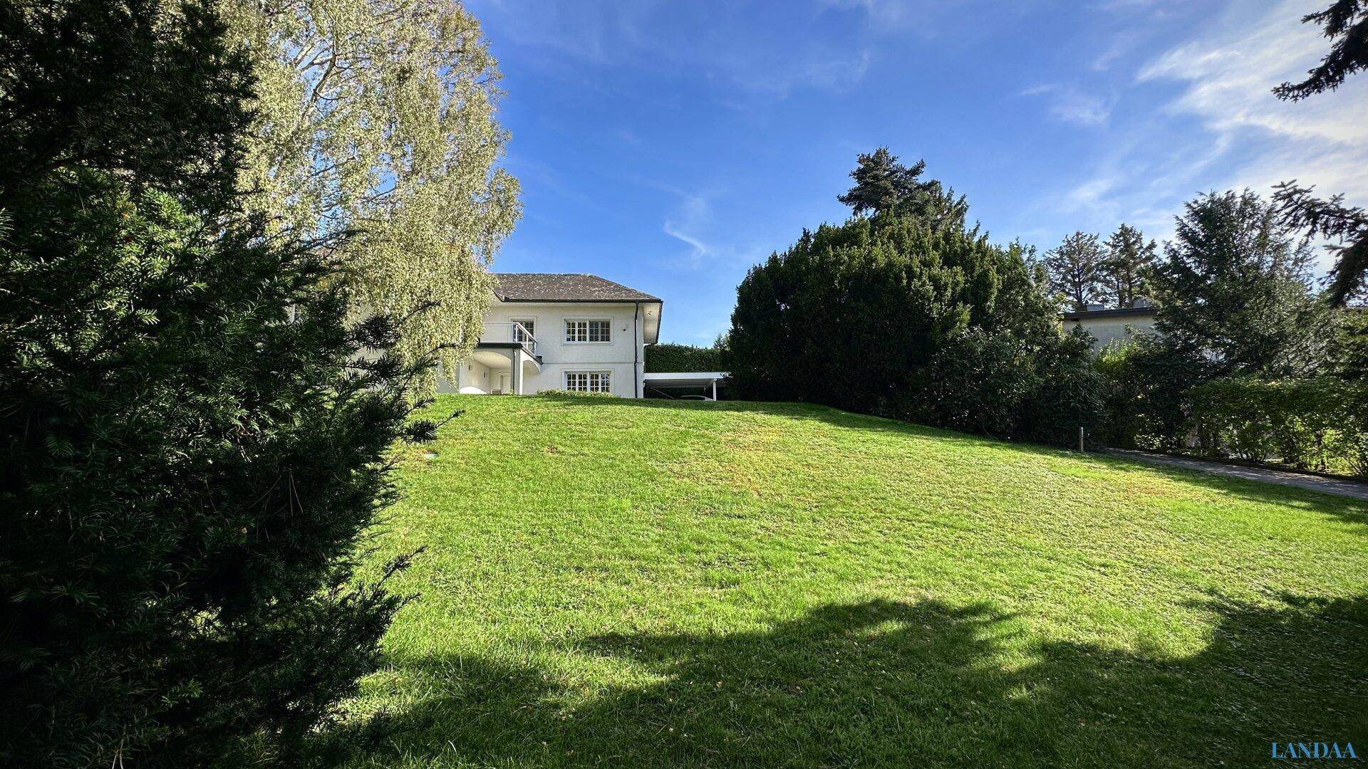 Große Rasenfläche im Garten mit Bäumen und Blick auf das Haus im Hintergrund.