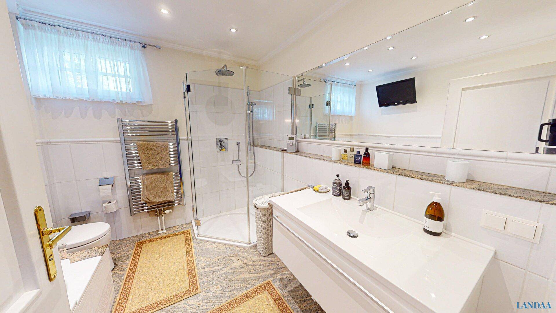 Modernes Badezimmer mit großer Dusche, Einzelwaschbecken und beheiztem Handtuchhalter.
