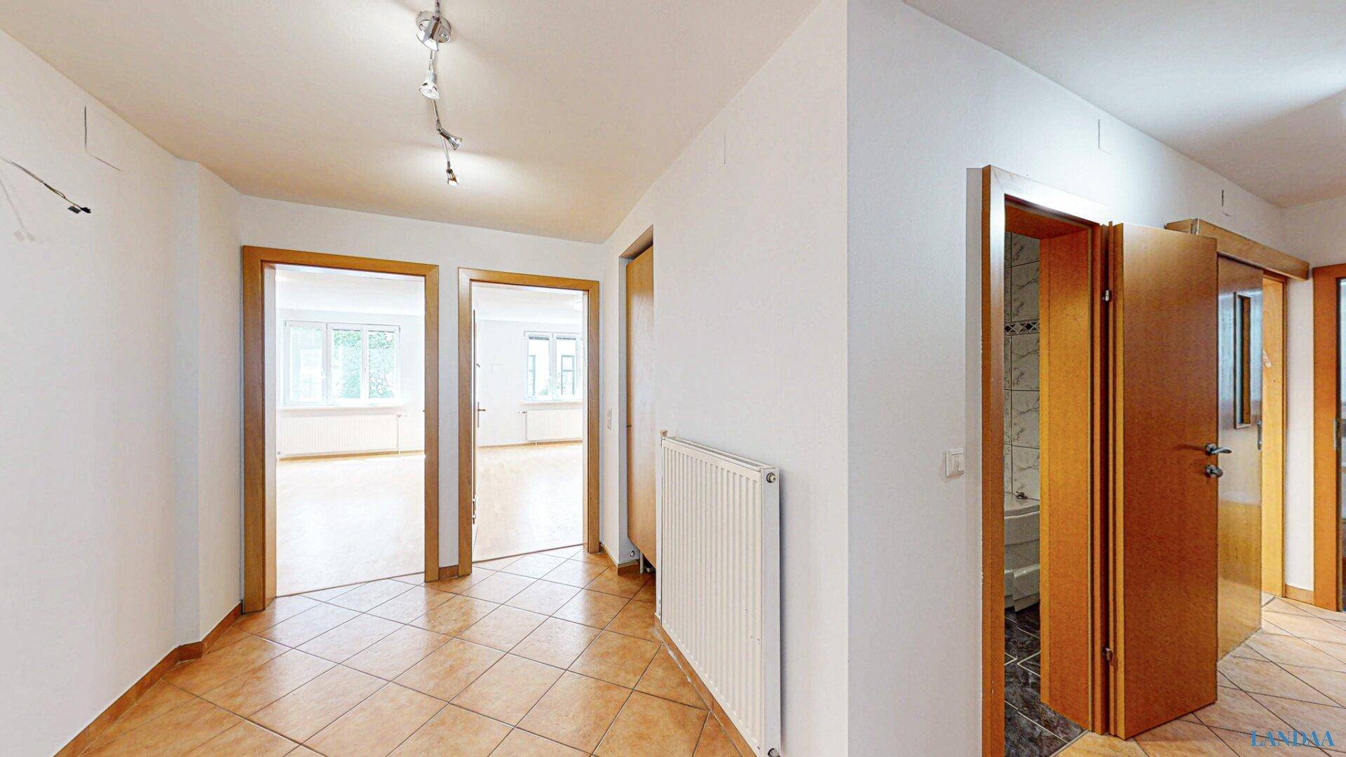 Geräumiger Flur mit Fliesenboden und Holztüren, der zu verschiedenen Zimmern führt.