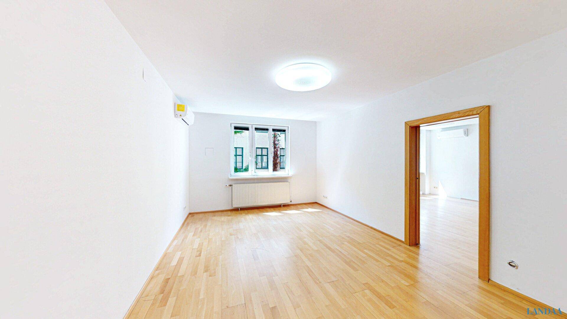 Helles, leeres Zimmer mit Holzboden und Fenster, bereit zur individuellen Gestaltung.