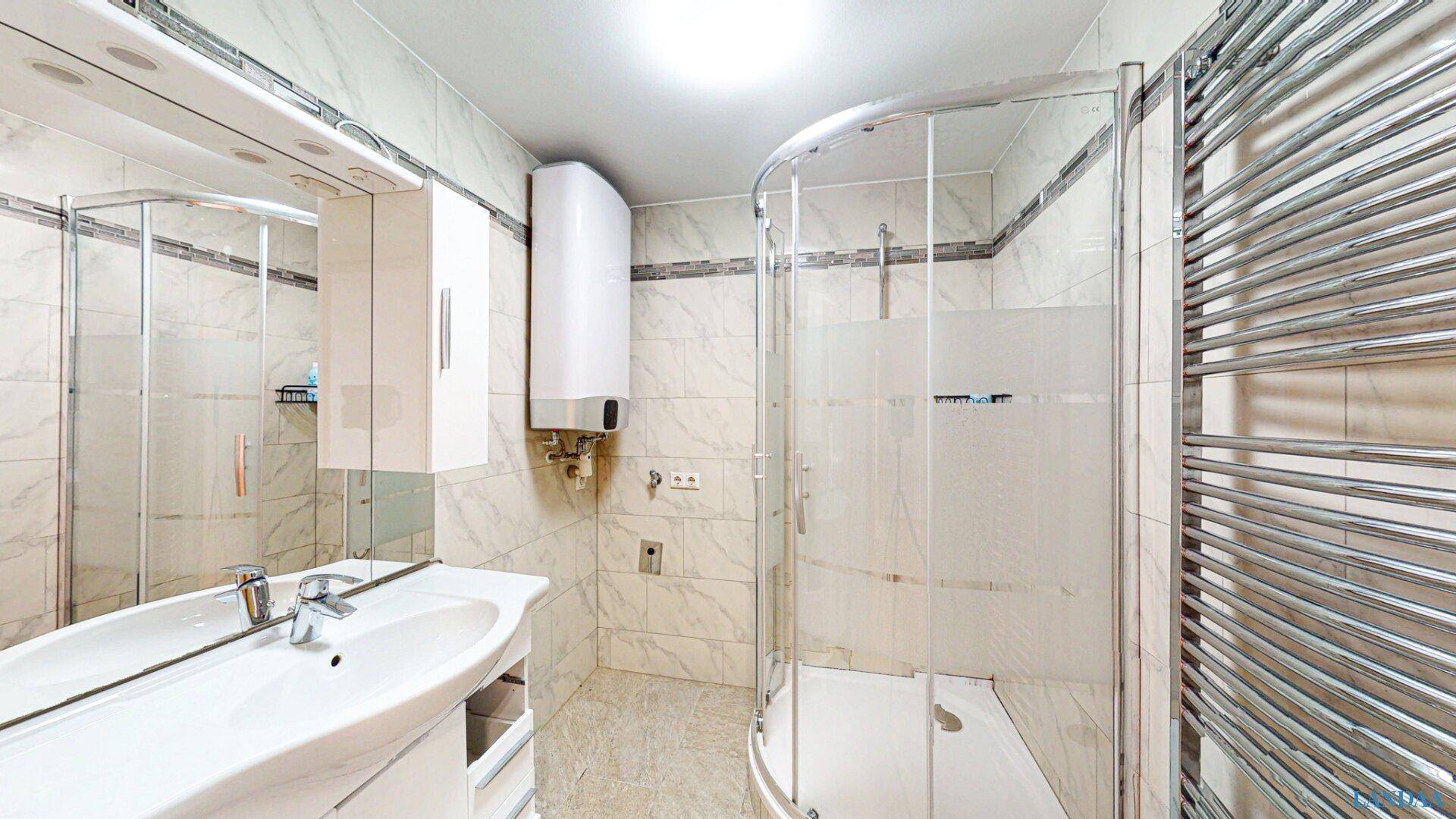 Modernes Badezimmer mit Duschkabine, Waschbecken und Handtuchheizkörper.