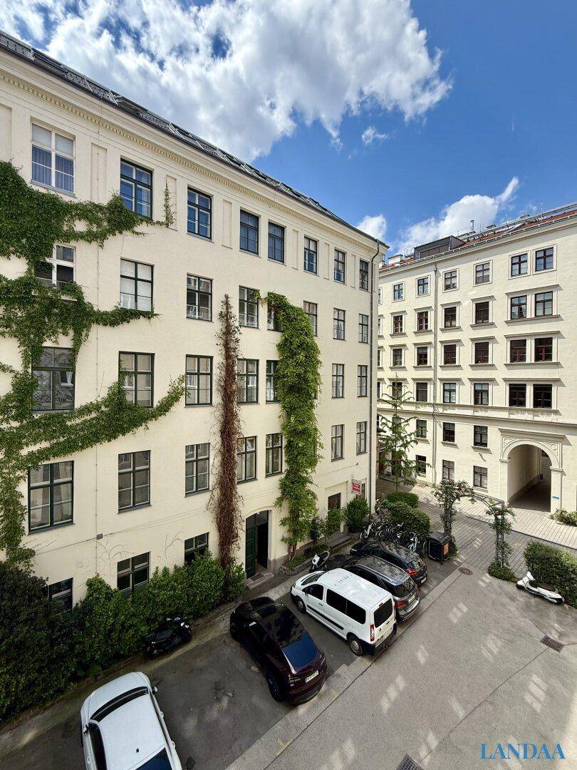 Innenhof eines Wohngebäudes mit Parkplätzen und begrünten Fassaden.