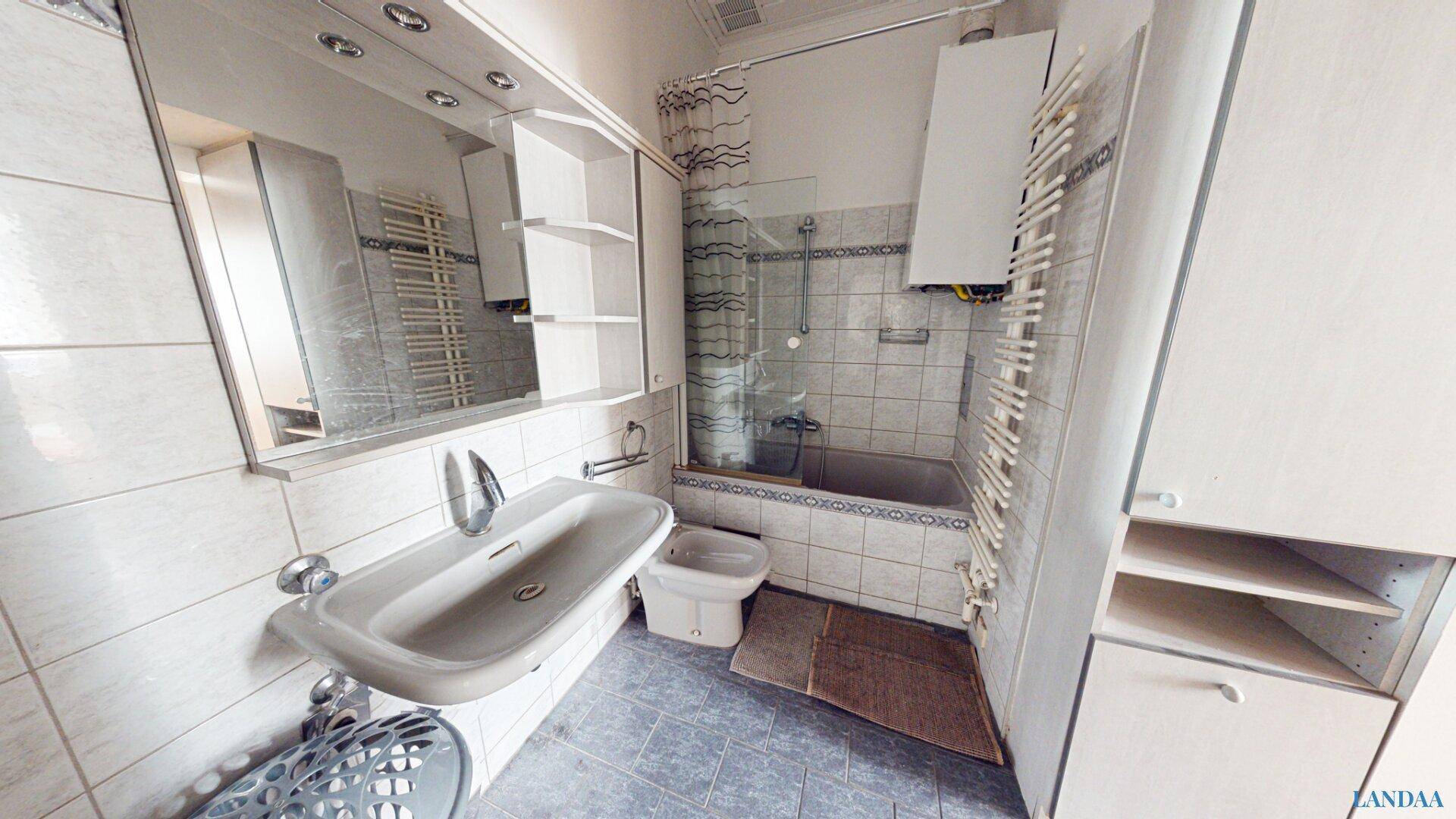 Badezimmer mit Badewanne, Dusche, Bidet und gefliesten Wänden in hellem Design.