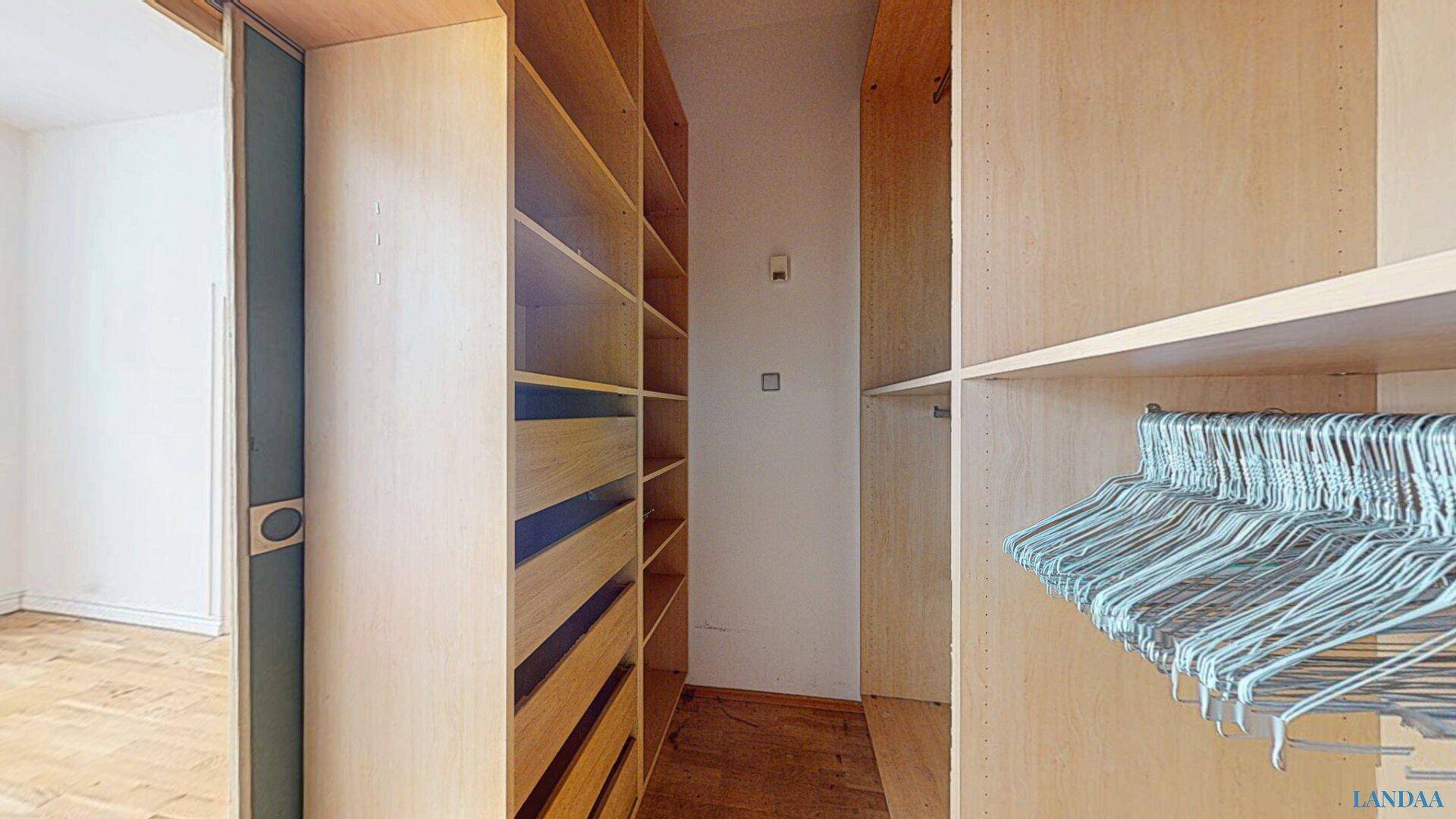 Geräumiger begehbarer Kleiderschrank mit vielen Regalen und Kleiderstangen.
