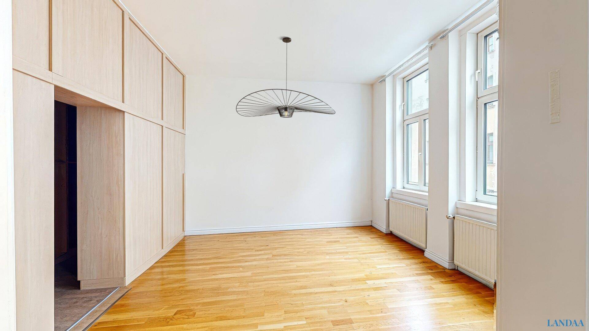 Helles, unmöbliertes Schlafzimmer mit Holzboden, großen Fenstern und Einbauschränken.