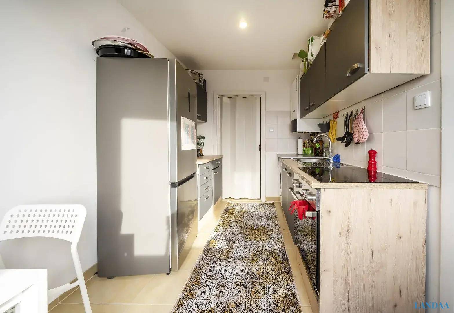 Funktionale Küche mit modernen grauen Schränken, Holzdetails und einem großen Kühlschrank, ideal für den täglichen Gebrauch.