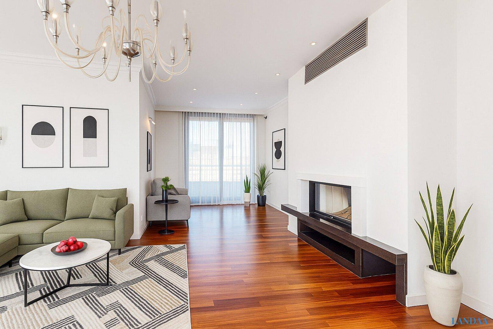 Geräumiges Wohnzimmer mit Holzboden, Kamin und Zugang zu einem Balkon.