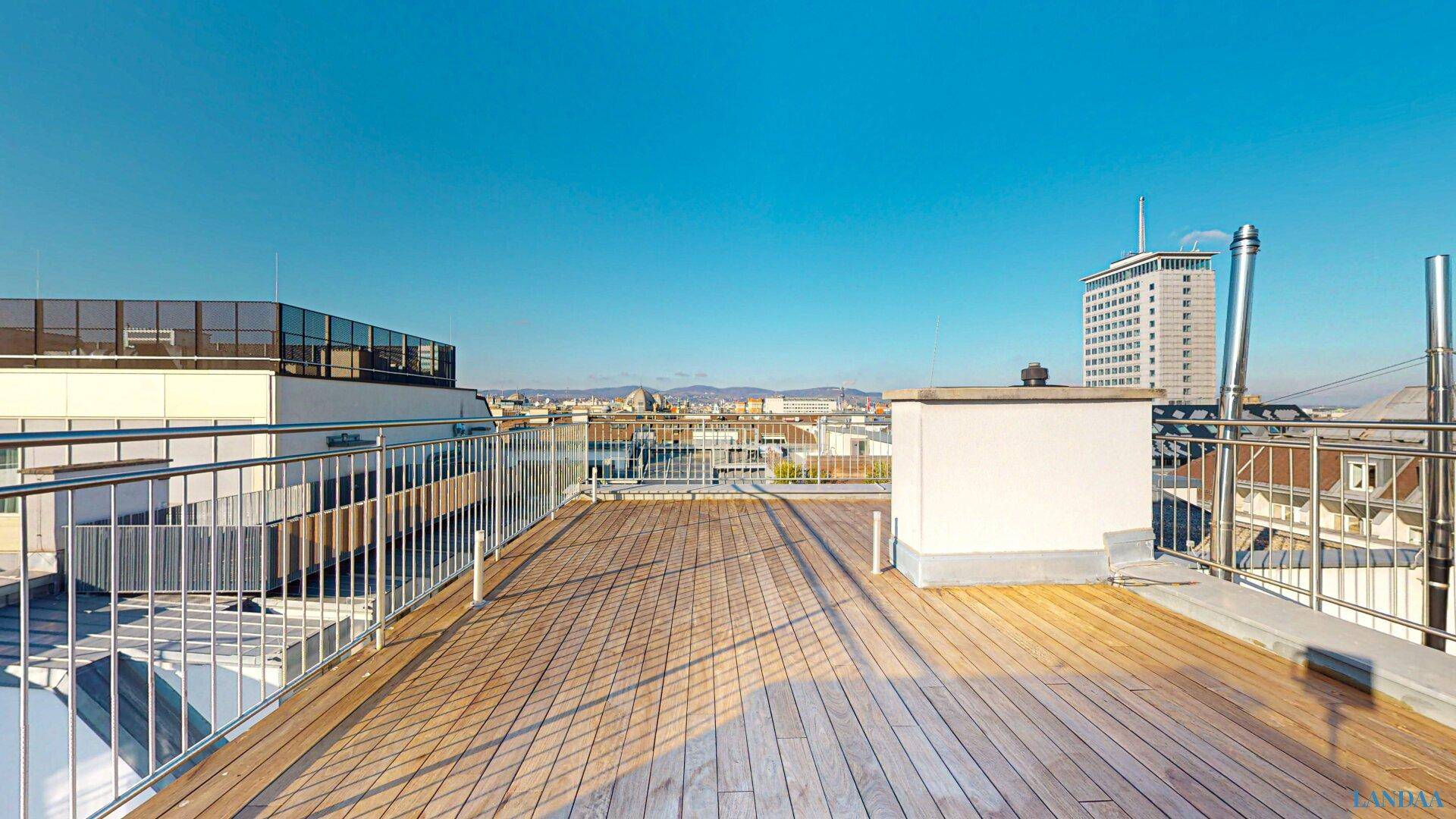 Weitläufige Dachterrasse mit Holzboden und Panoramablick über die Stadt.