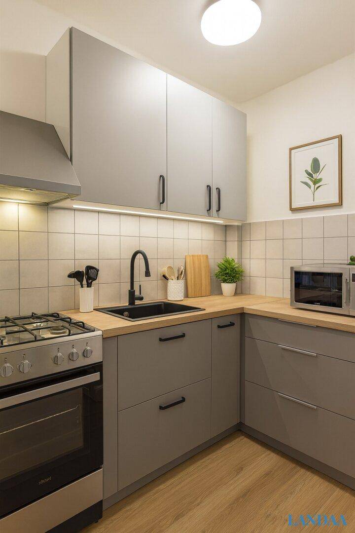 Moderne Küche mit grauen Schränken, Holz-Arbeitsplatte und Gasherd, ausgestattet mit Mikrowelle.