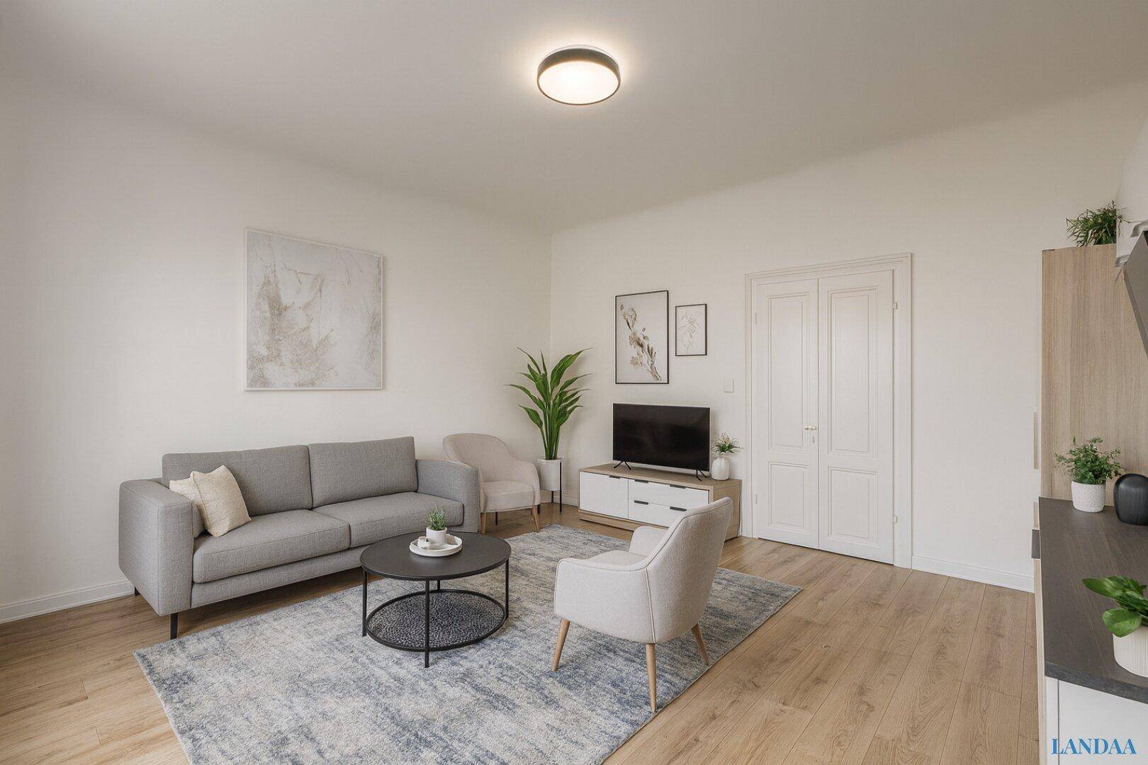 Gemütliches Wohnzimmer mit grauem Sofa, zwei Sesseln und Holzboden, ergänzt durch einen Teppich.