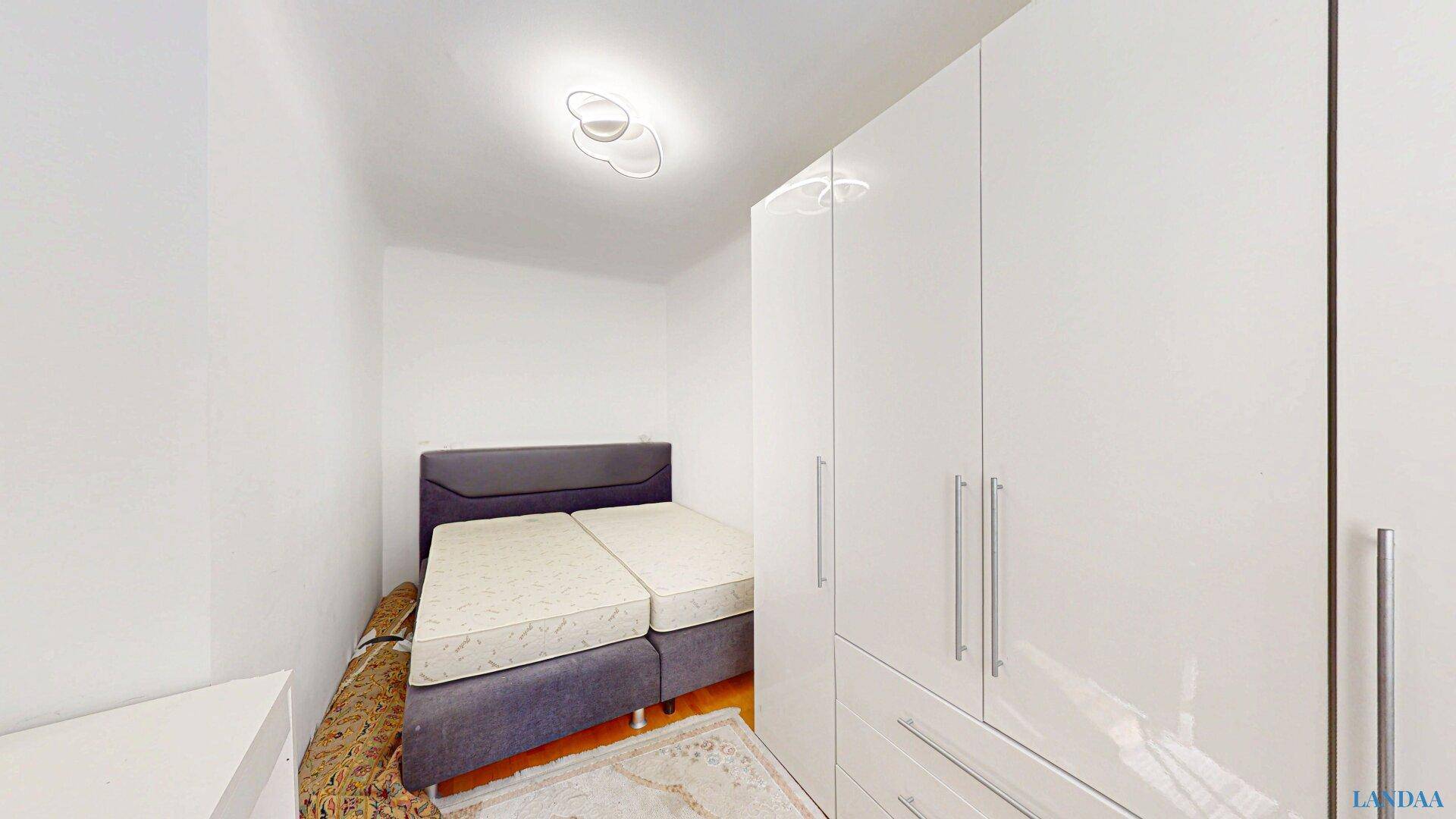 Schlafzimmer mit zwei Matratzen und einem großen, modernen weißen Kleiderschrank.