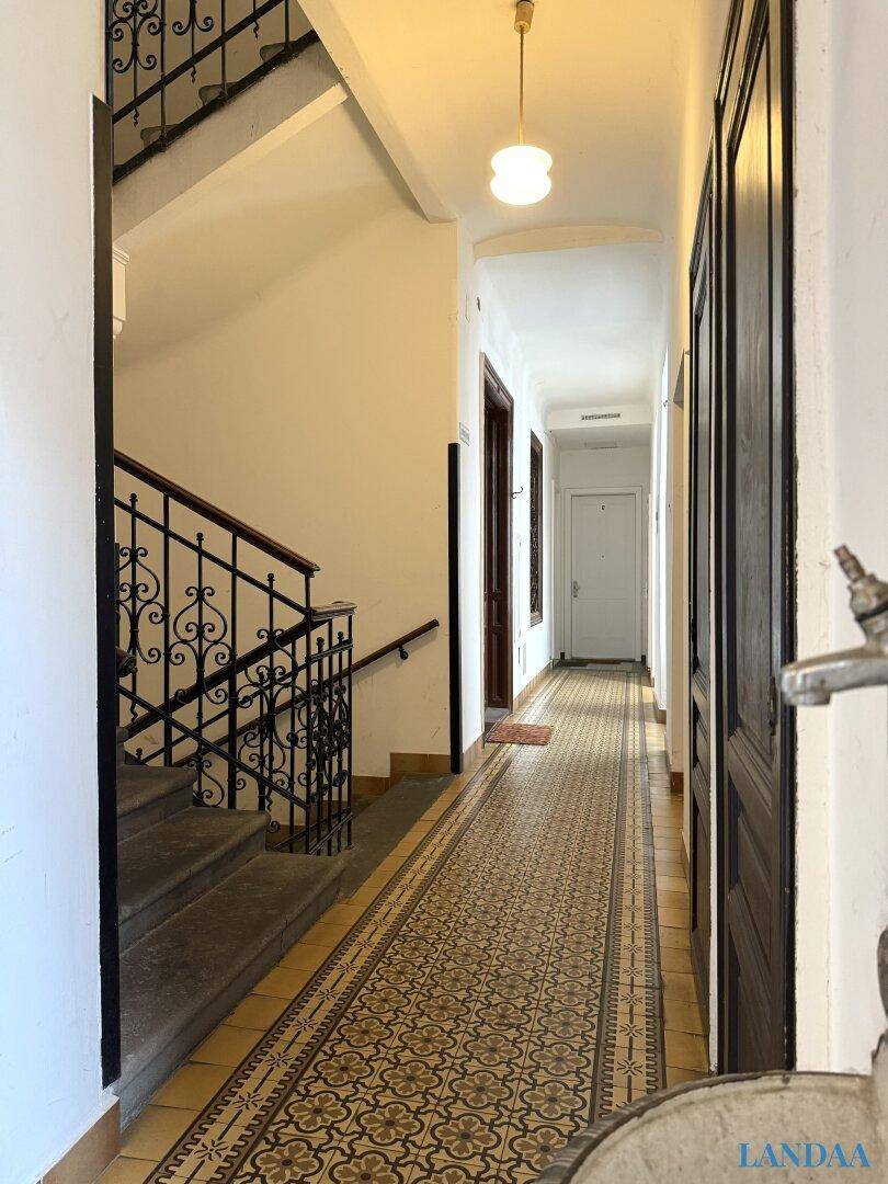 Historischer Treppenaufgang mit kunstvollem Geländer und gemustertem Fliesenboden in einem Altbau.