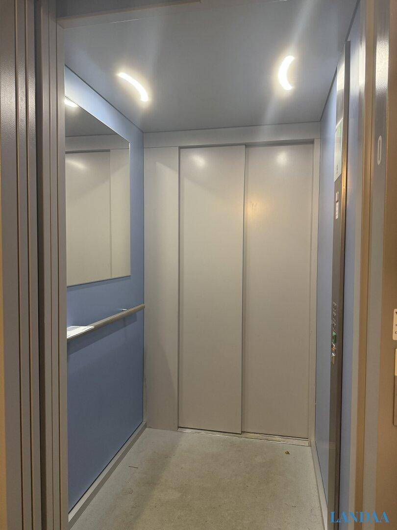 Moderner Aufzug mit hellen Wänden und Spiegelfläche im Gebäude.