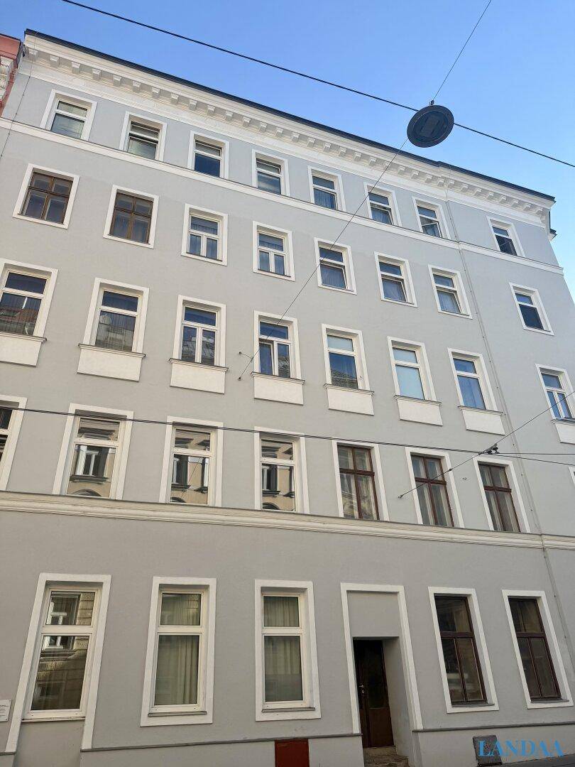Historische Fassade eines Mehrfamilienhauses mit vielen Fenstern und klassischer Architektur.