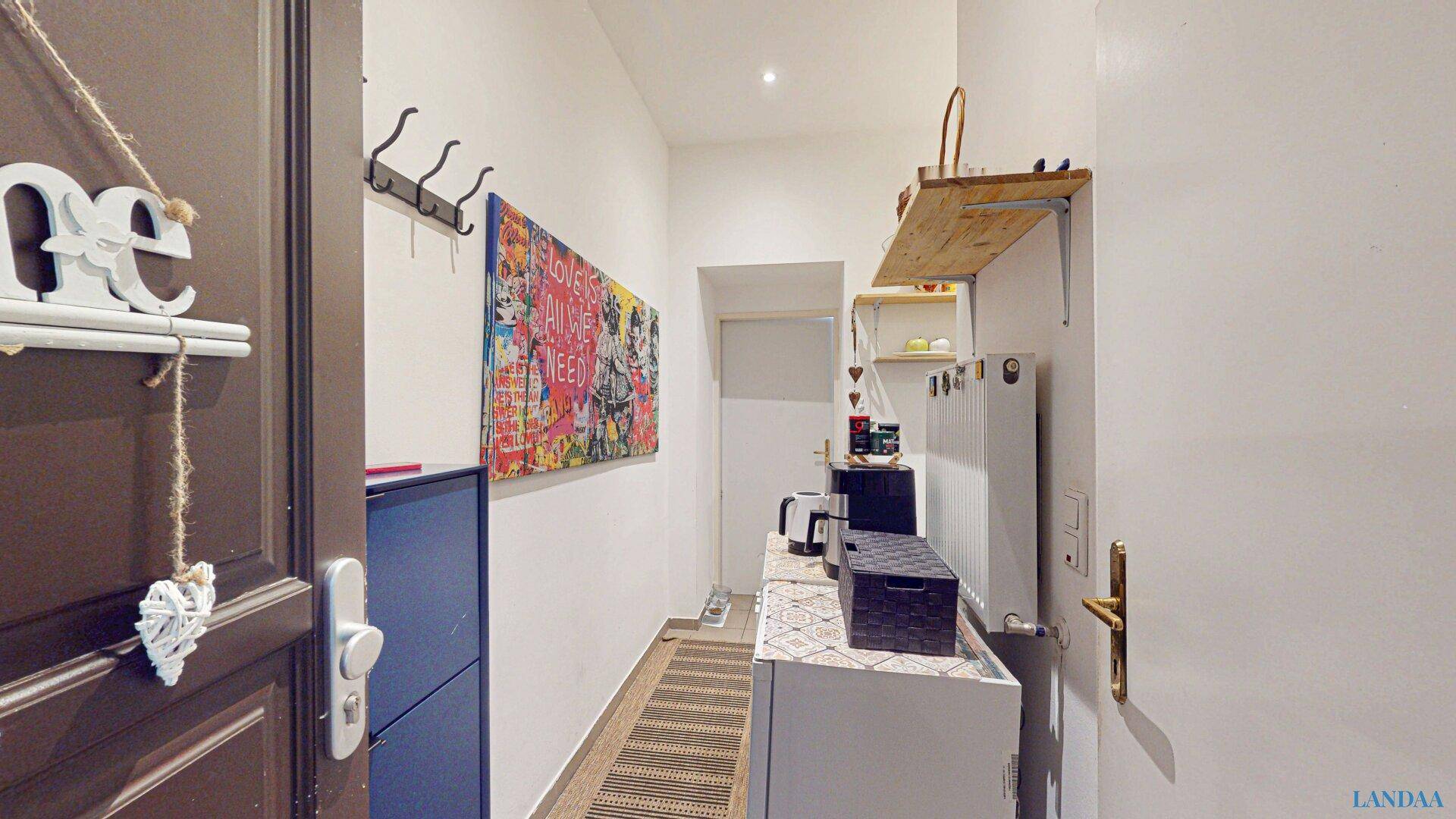 Heller Eingangsbereich mit Garderobe, Schuhschrank und dekorativen Elementen.