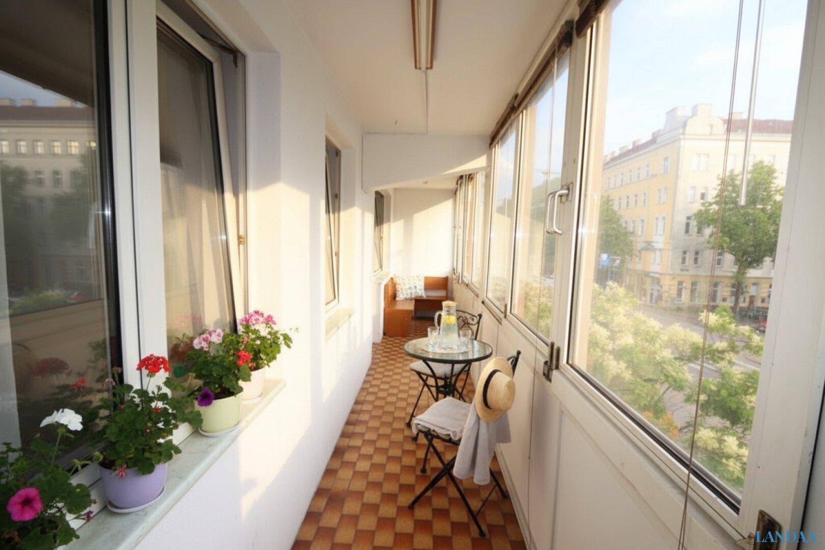 Gemütliche verglaste Loggia mit Sitzgelegenheiten, Pflanzen und Stadtblick.