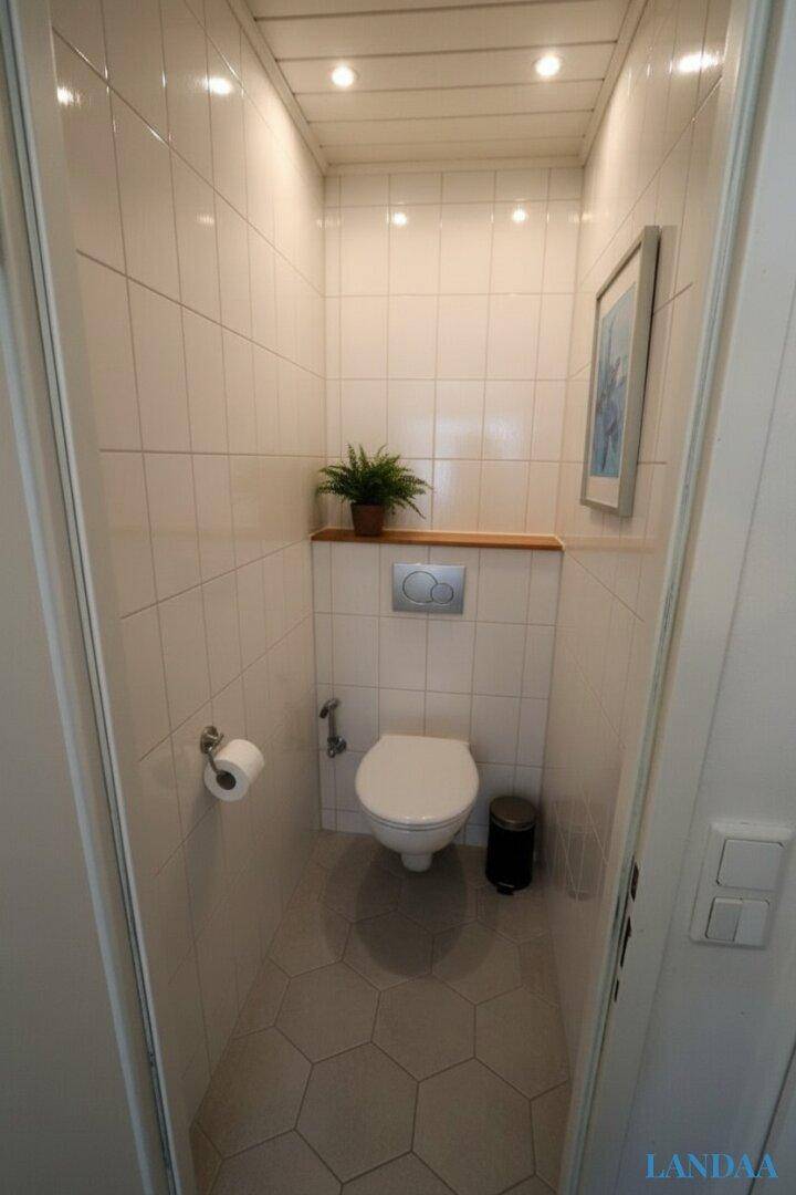 Kleines WC mit hellen Fliesen, wandhängender Toilette und sechseckigem Bodenbelag.