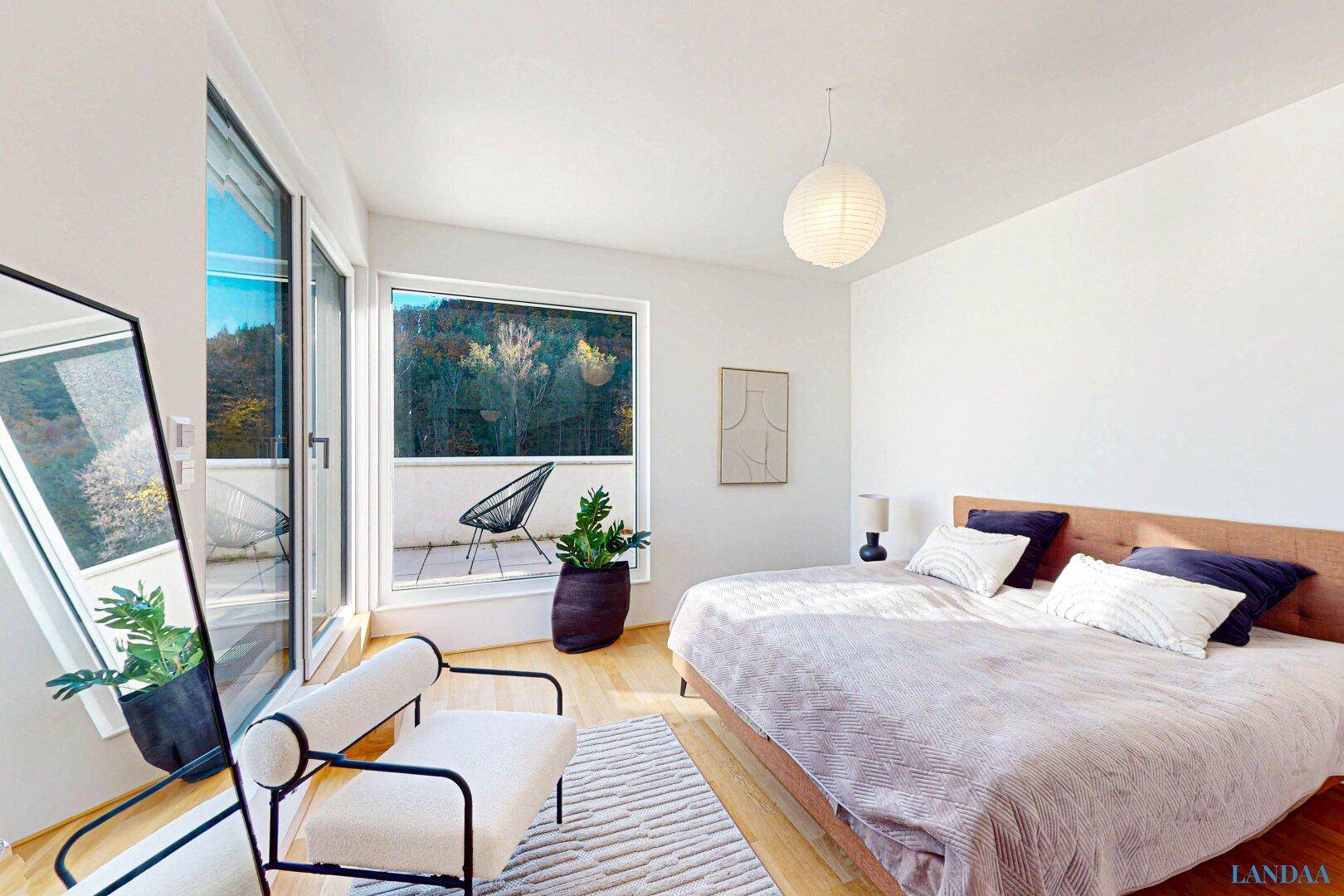 Helles Schlafzimmer mit Holzboden, großem Bett und Zugang zu einem kleinen Balkon mit Waldblick.