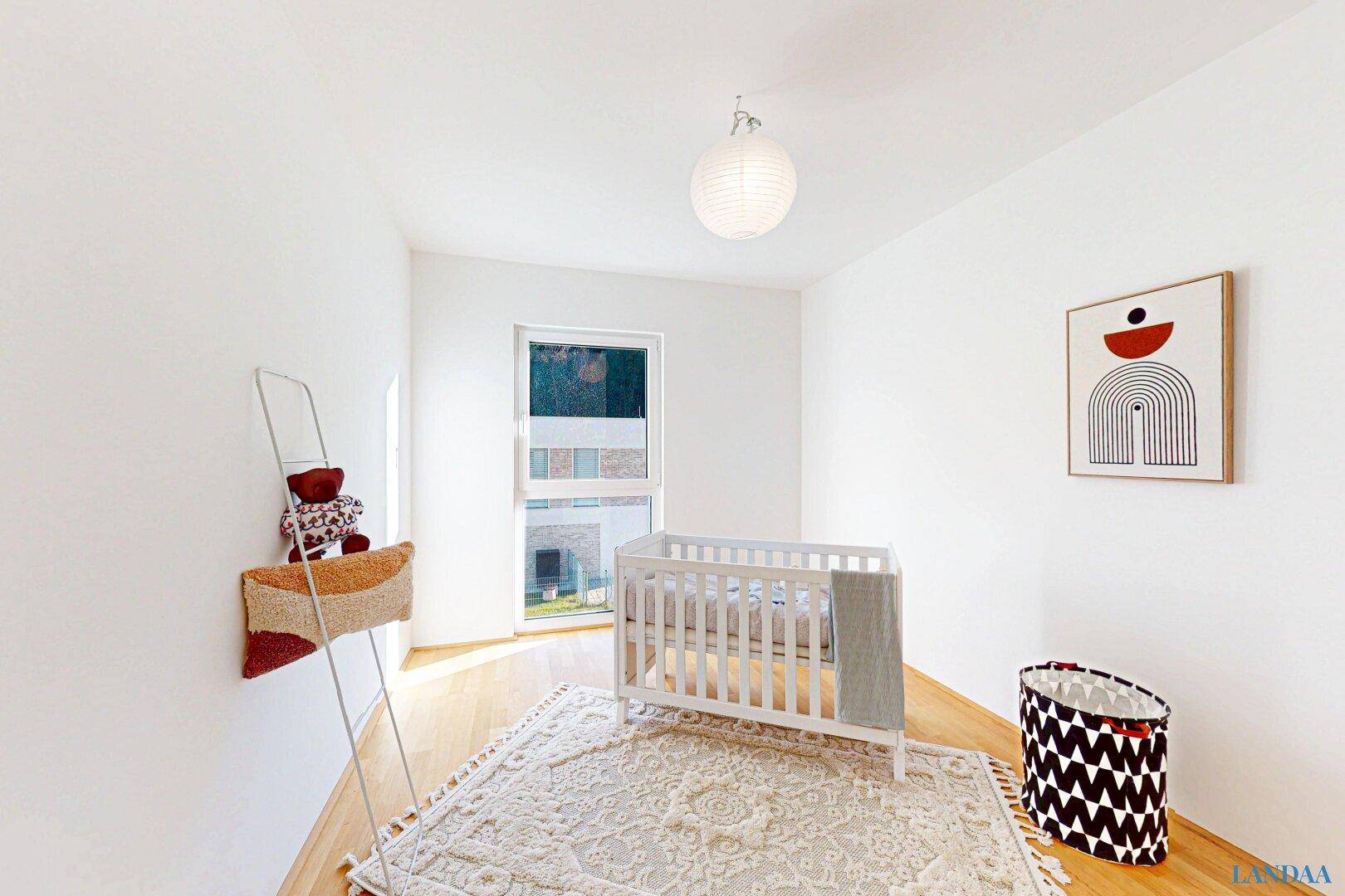 Helles Kinderzimmer mit Holzboden, Babybett und Blick auf die umliegende Bebauung.