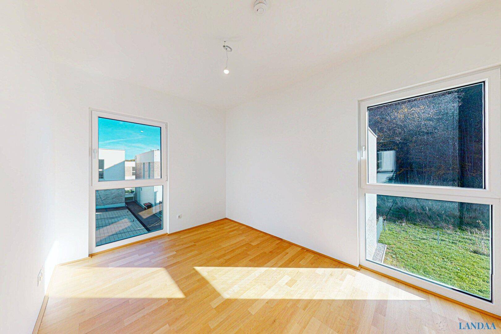 Heller, leerer Raum mit großen Fenstern und hellem Parkettboden, ideal für Schlaf- oder Wohnzimmer.