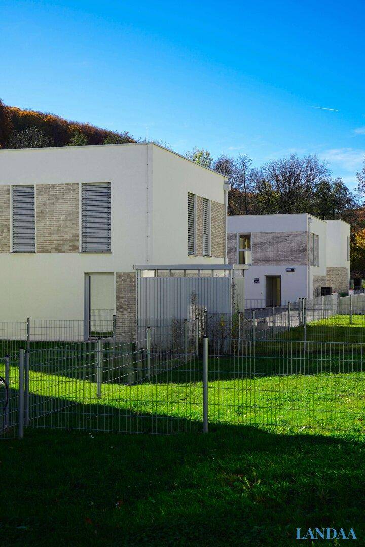 Reihe moderner Einfamilienhäuser mit schlichter Architektur und grünen Gärten im Herbstlicht.