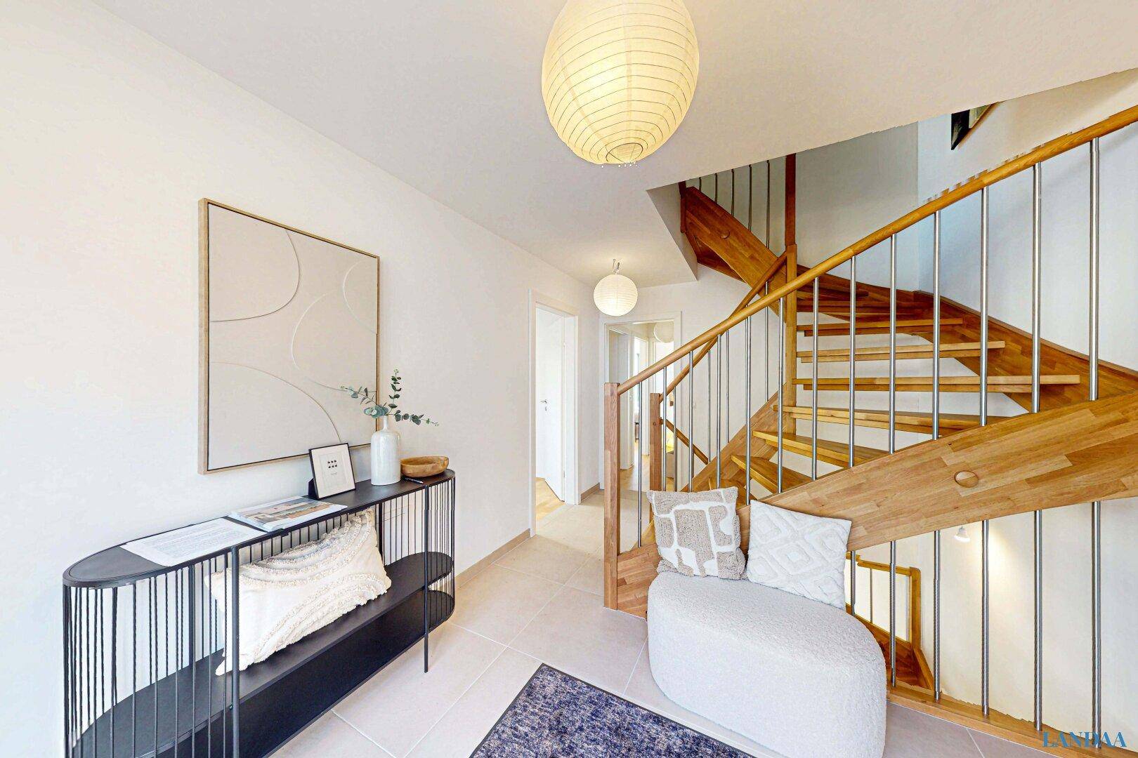 Heller Eingangsbereich mit Holztreppe, Fliesenboden und moderner Dekoration.