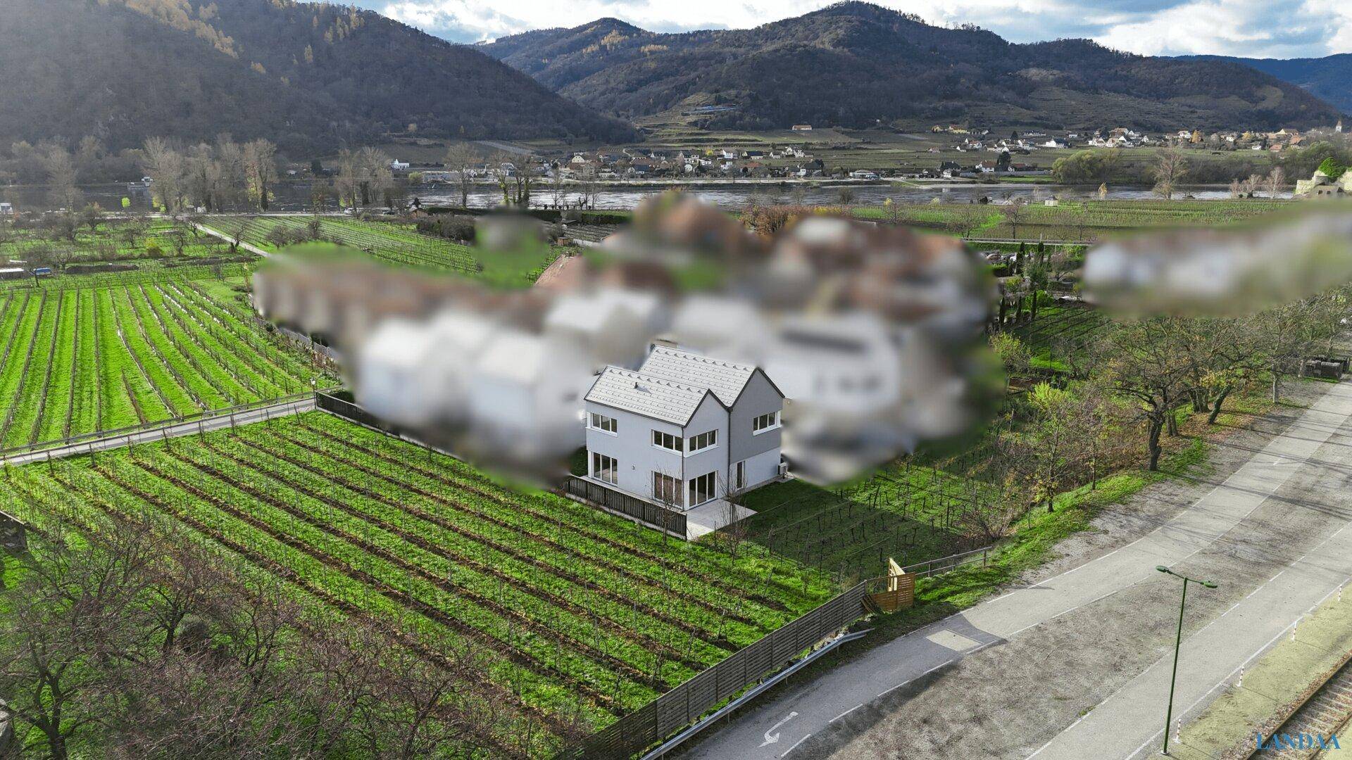 Luftaufnahme eines modernen Hauses inmitten von Weinbergen mit umliegender Natur.