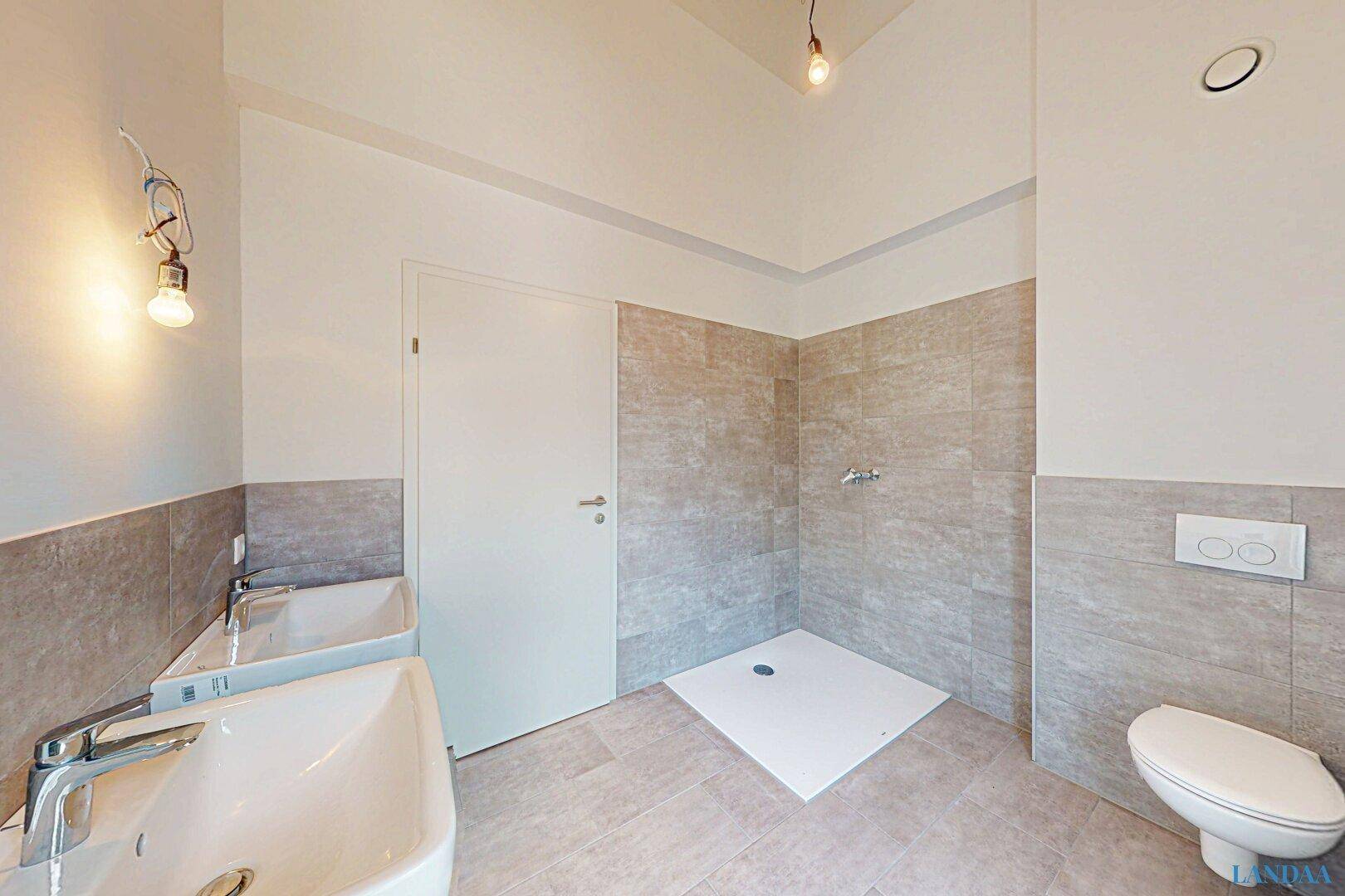 Modernes Badezimmer mit zwei Waschbecken, begehbarer Dusche und grauen Fliesen.
