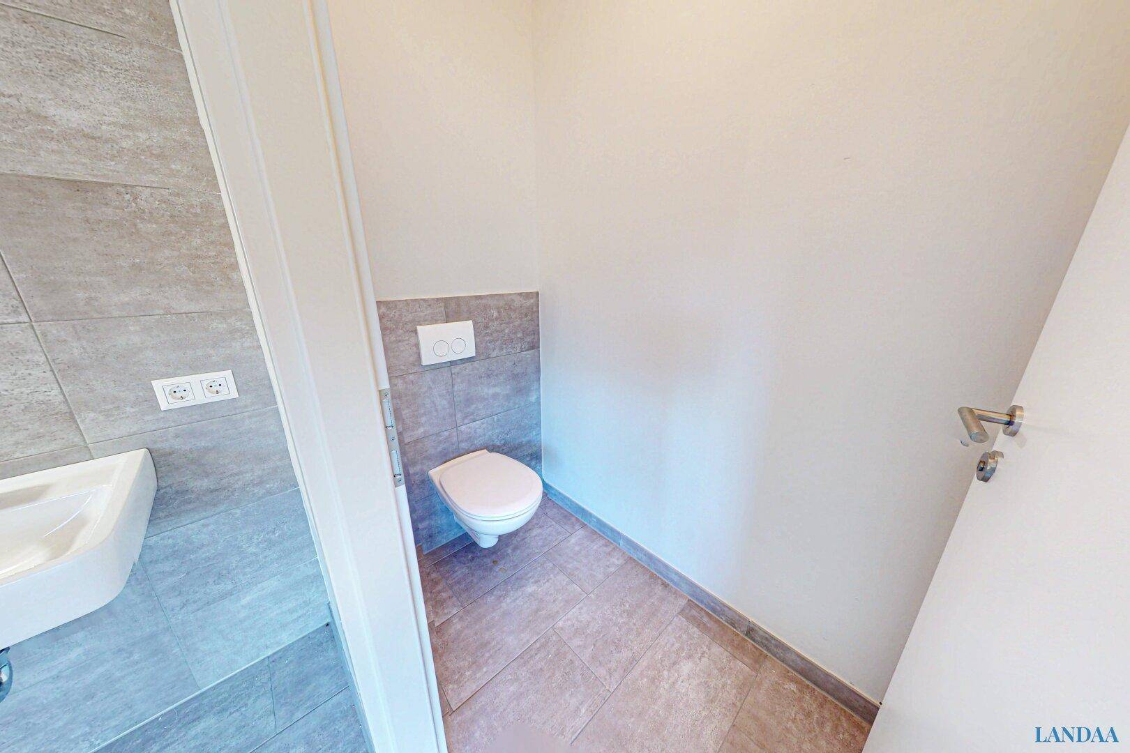 Kleines Gäste-WC mit Wand-WC und teilweiser Fliesenverkleidung in modernem Design.