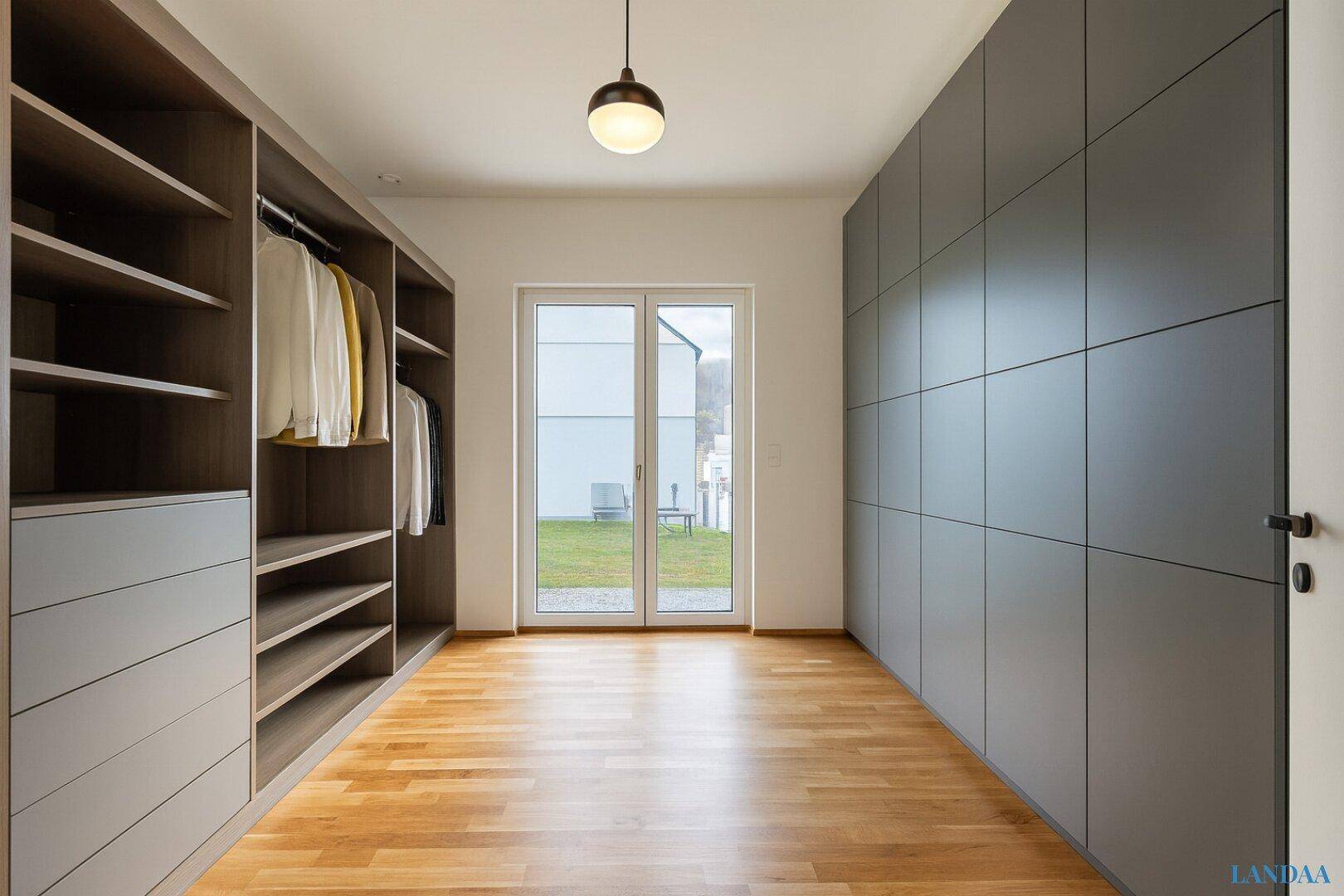 Geräumiger begehbarer Kleiderschrank mit integrierten Regalen und Schränken, mit Zugang zum Garten.