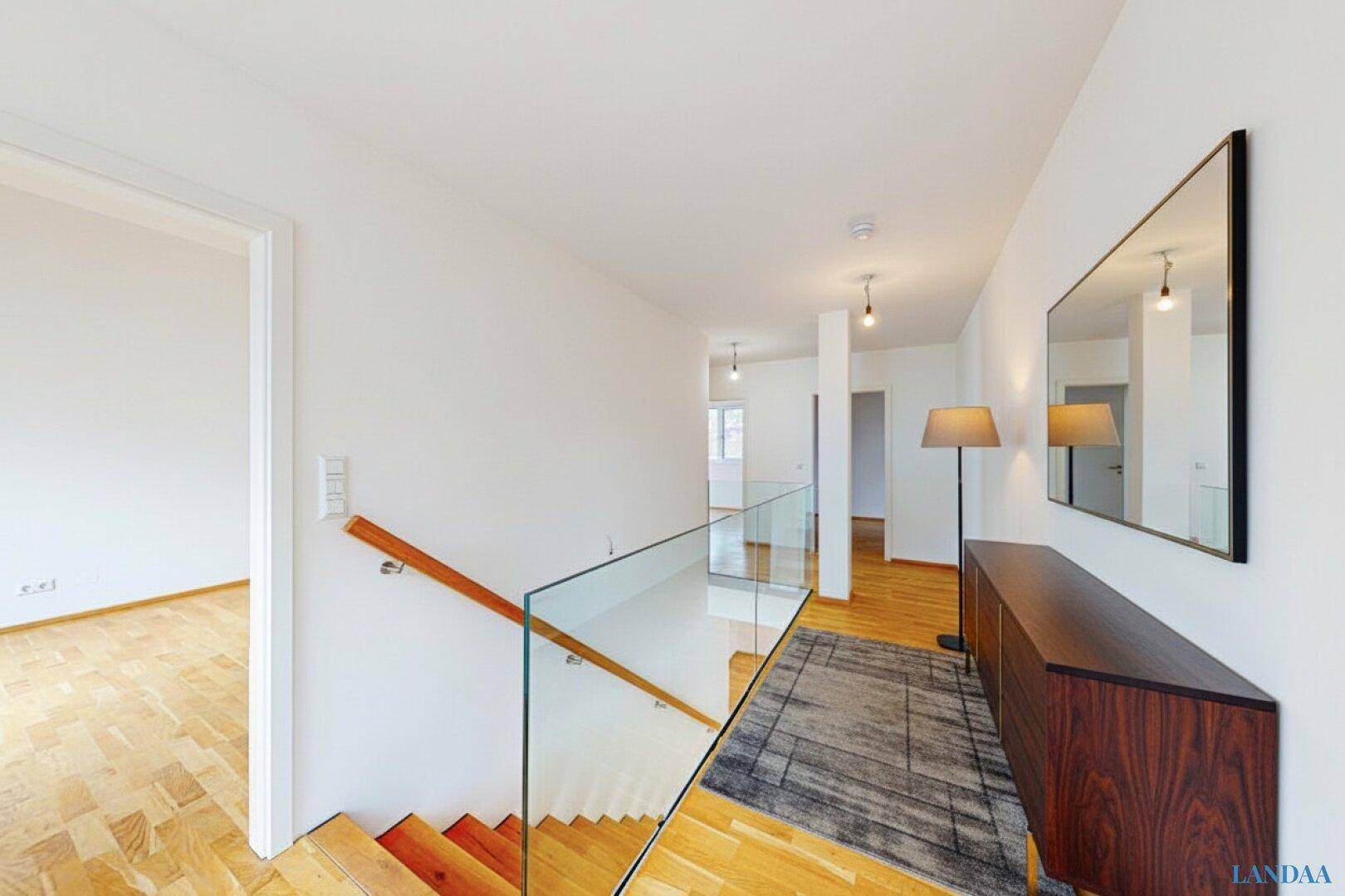 Stilvoller Flur im Obergeschoss mit Holzboden, modernem Sideboard und großem Spiegel.