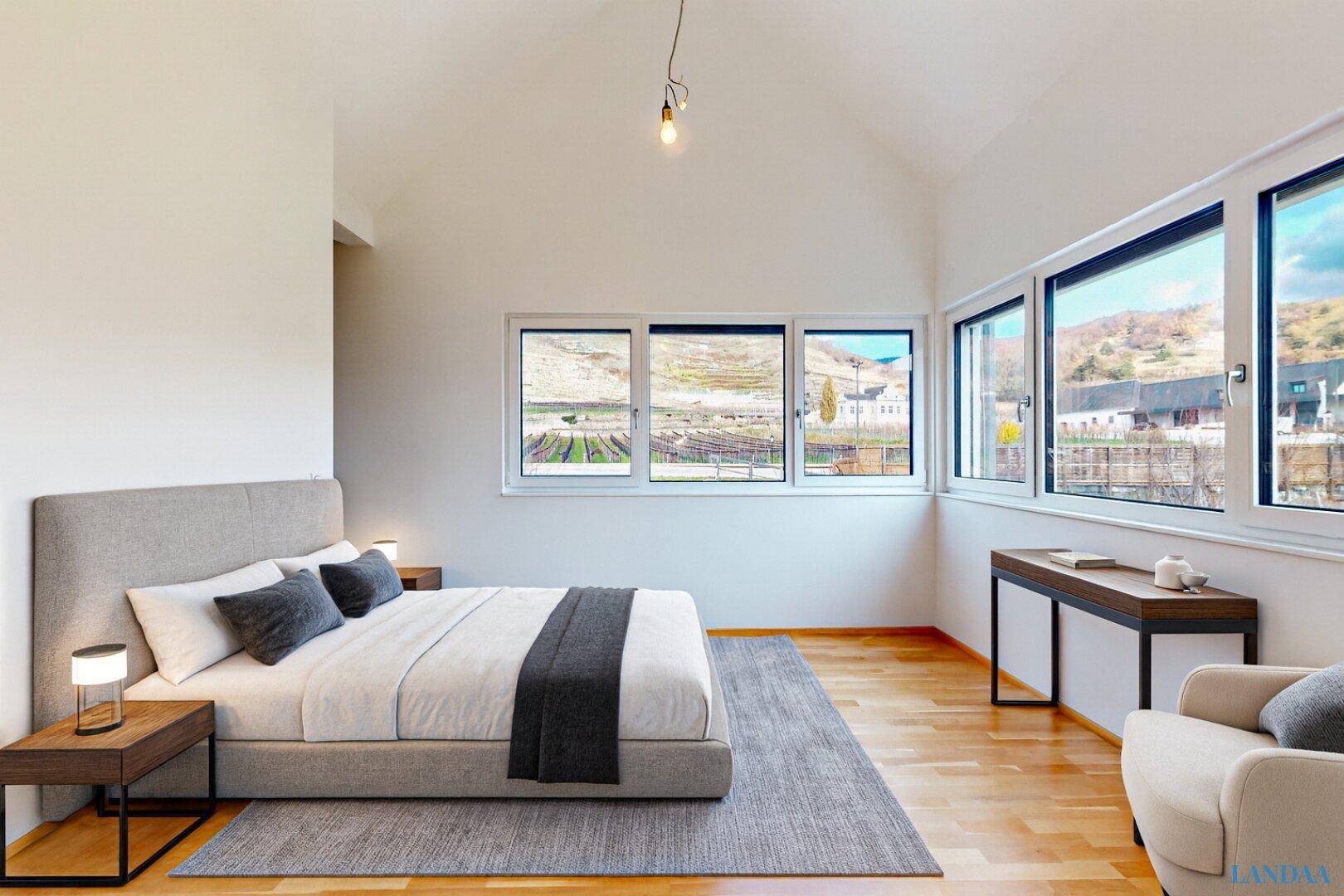 Helles Schlafzimmer mit hohen Decken, großen Fenstern und weitem Blick auf die Landschaft.