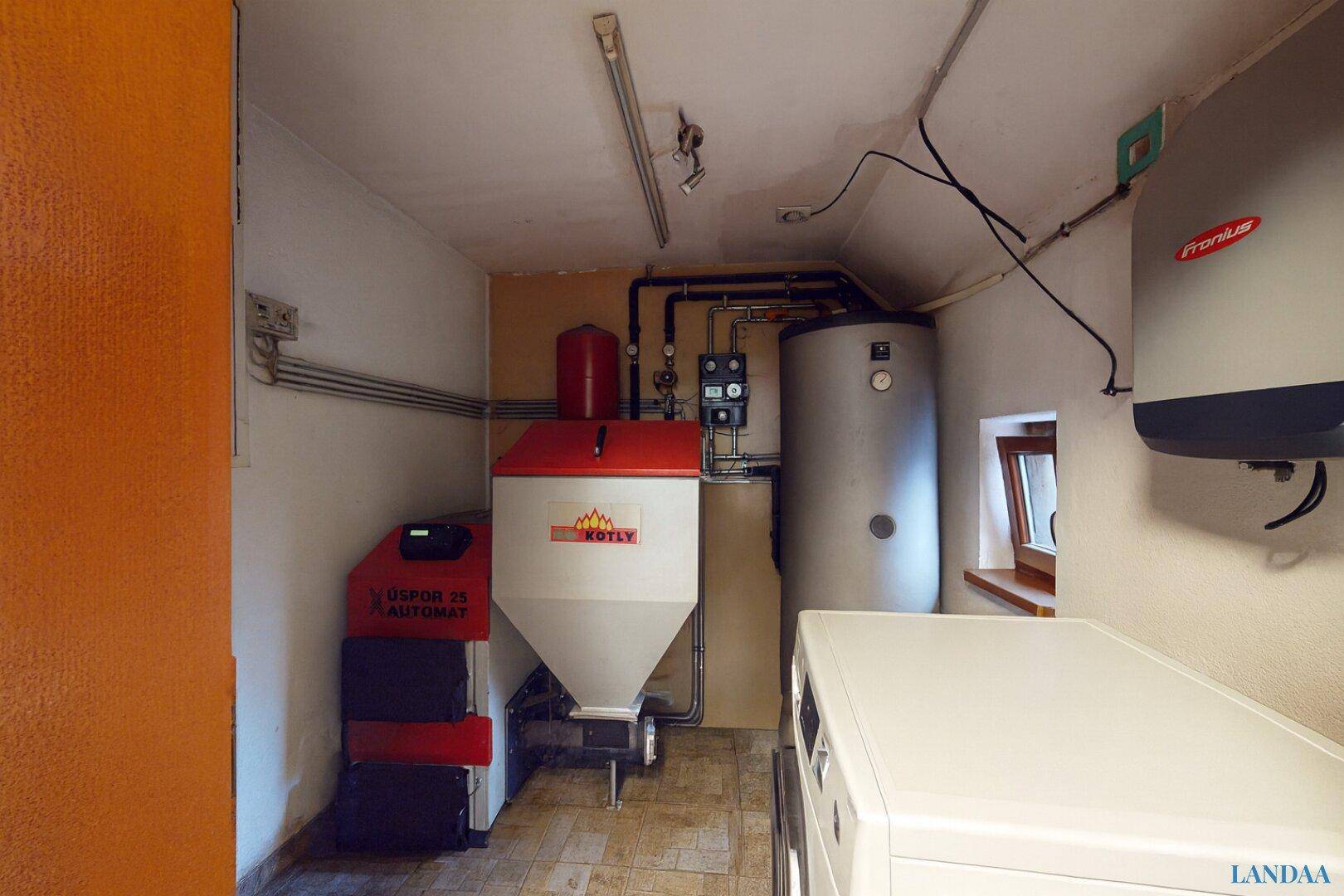 Technikraum mit Heizungsanlage, Warmwasserspeicher und Waschmaschine, funktional eingerichtet.