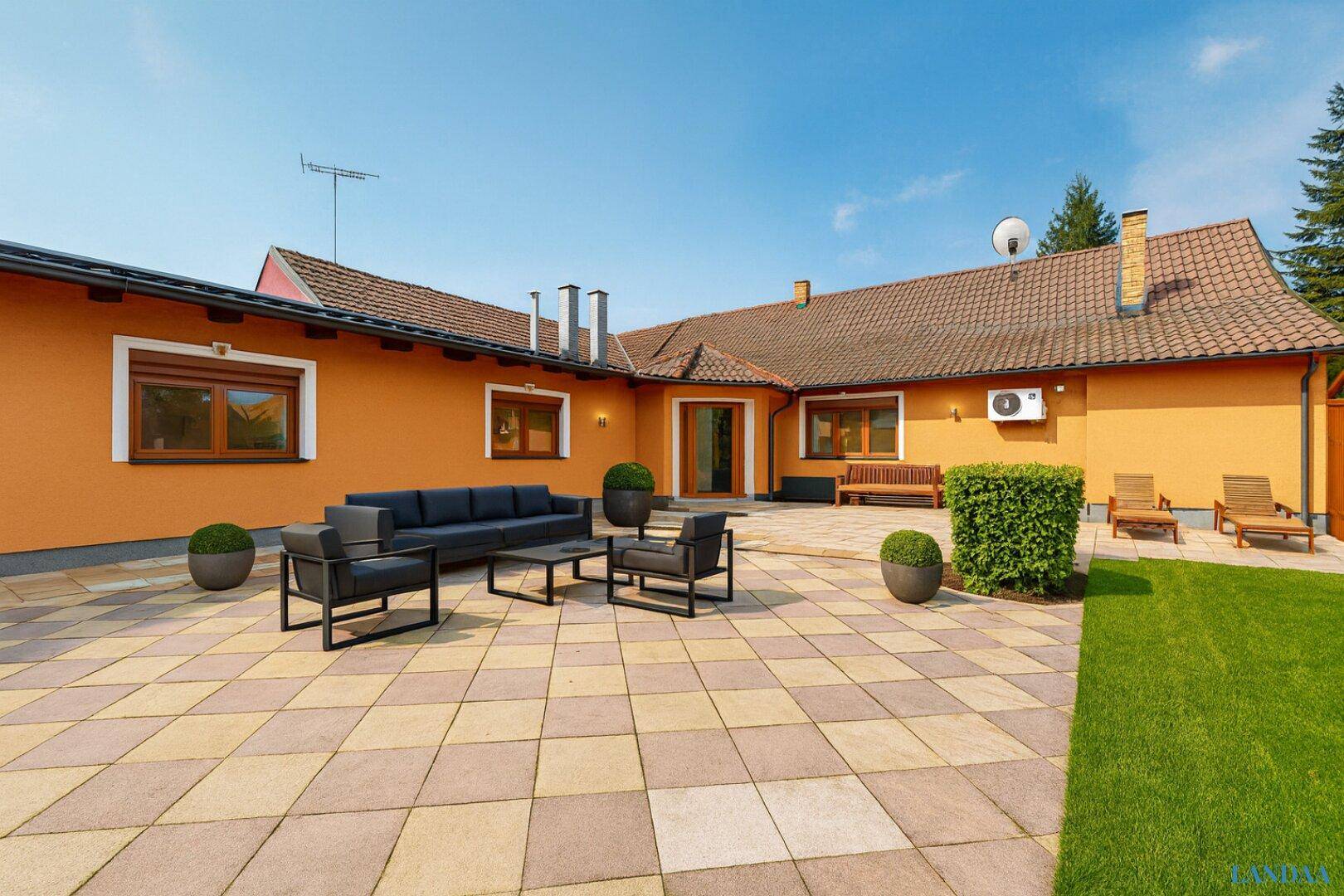Weitläufige Terrasse mit modernen Gartenmöbeln und Blick auf den gepflegten Rasenbereich.