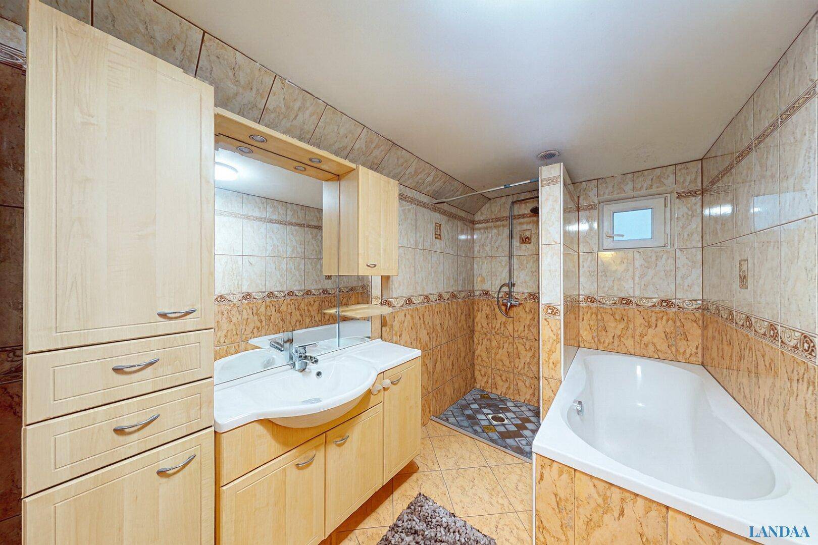 Funktionales Badezimmer mit Badewanne, Dusche und Holzschränken, komplett gefliest.