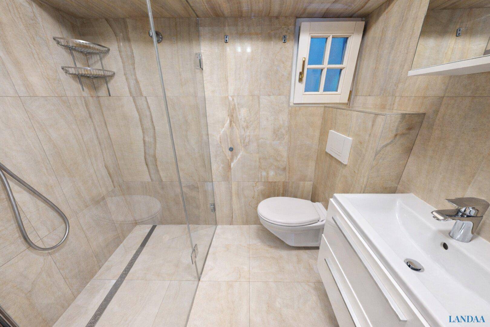 Modernes Badezimmer mit begehbarer Dusche, Wand-WC und Fenster, komplett gefliest.