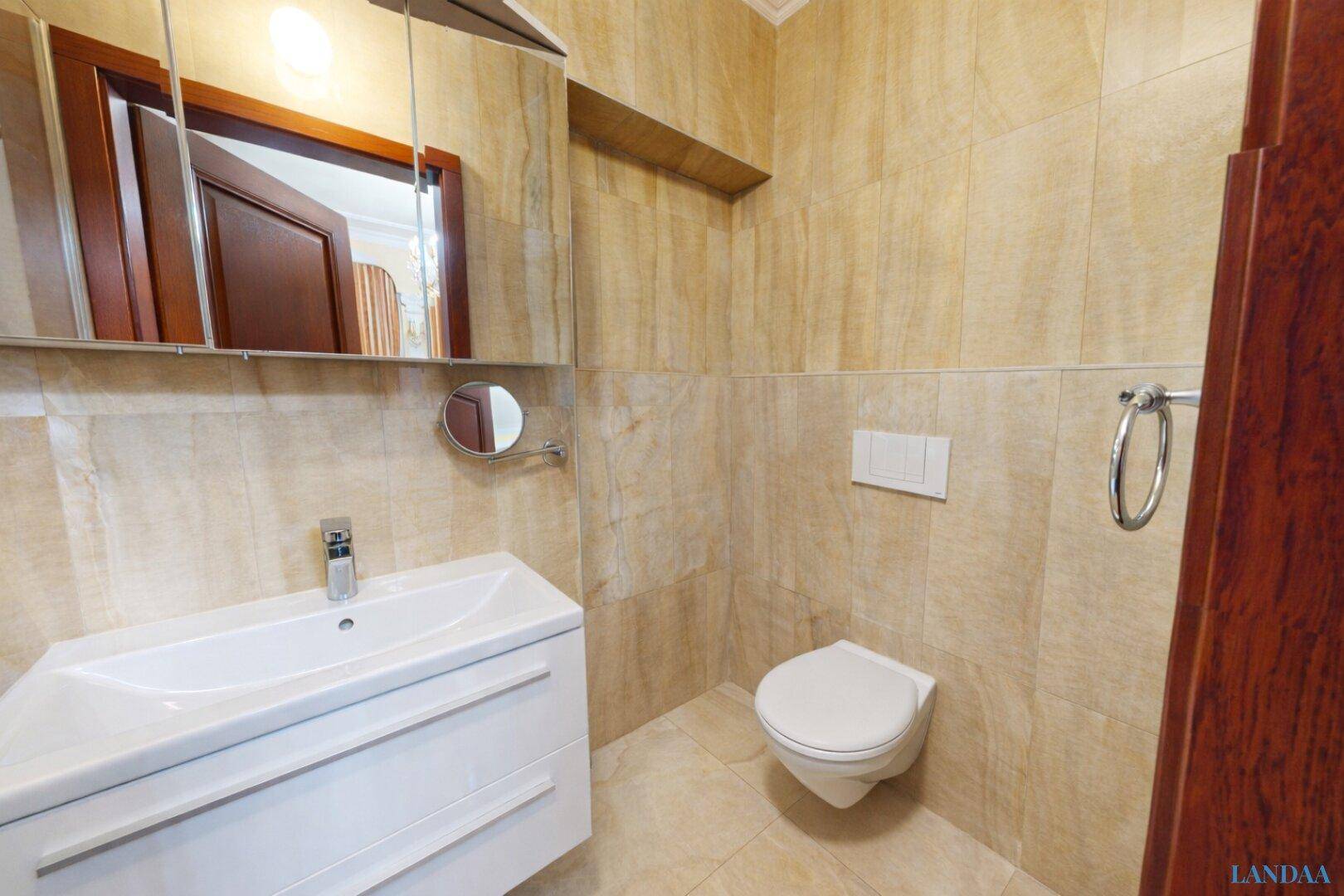 Kleines Gäste-WC mit Waschbecken, Wand-WC und Spiegelschrank, vollständig gefliest.