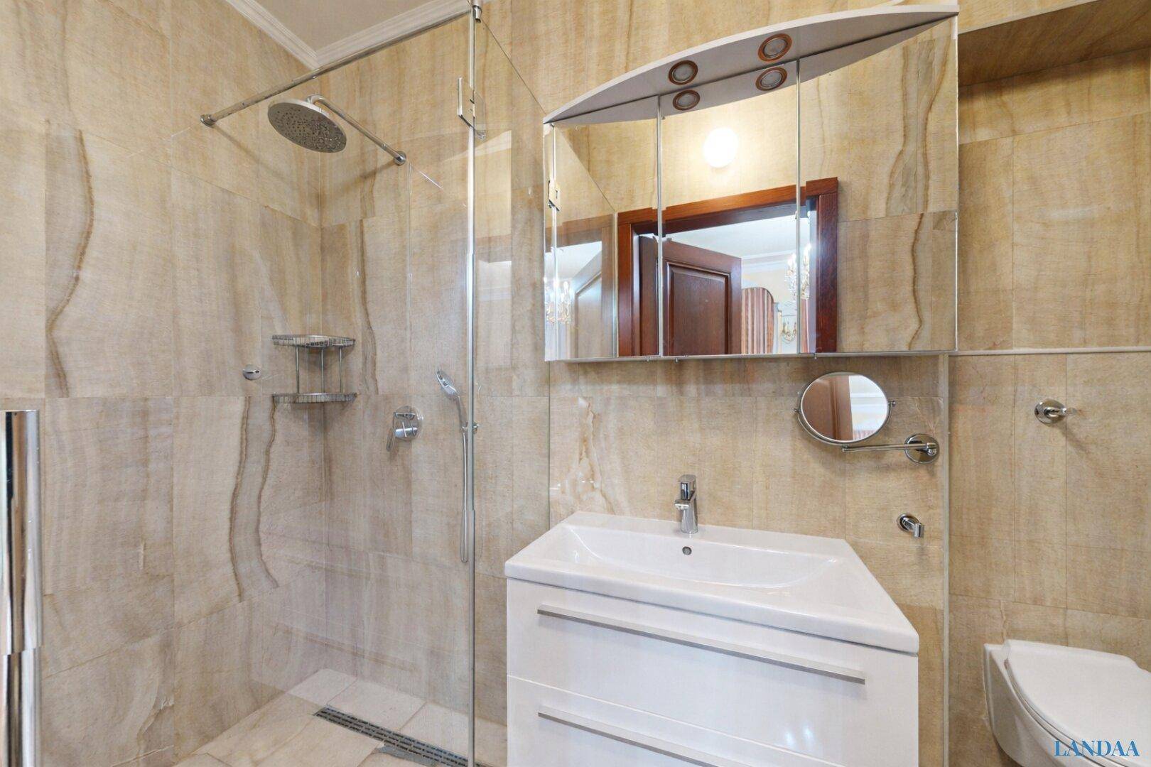Helles Badezimmer mit großer begehbarer Dusche, Waschbecken und Spiegelschrank, modern gefliest.
