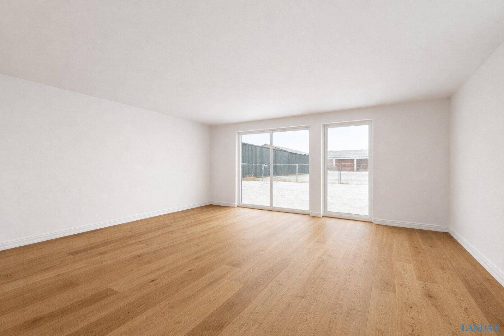 Heller Wohnraum mit Holzboden, weißen Wänden und großen Fenstern mit Blick ins Grüne.