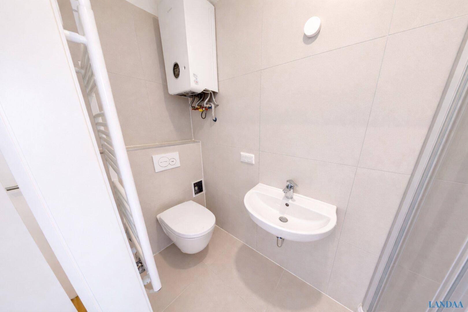 Modernes Badezimmer mit wandhängendem WC, Waschbecken und Warmwasserboiler.