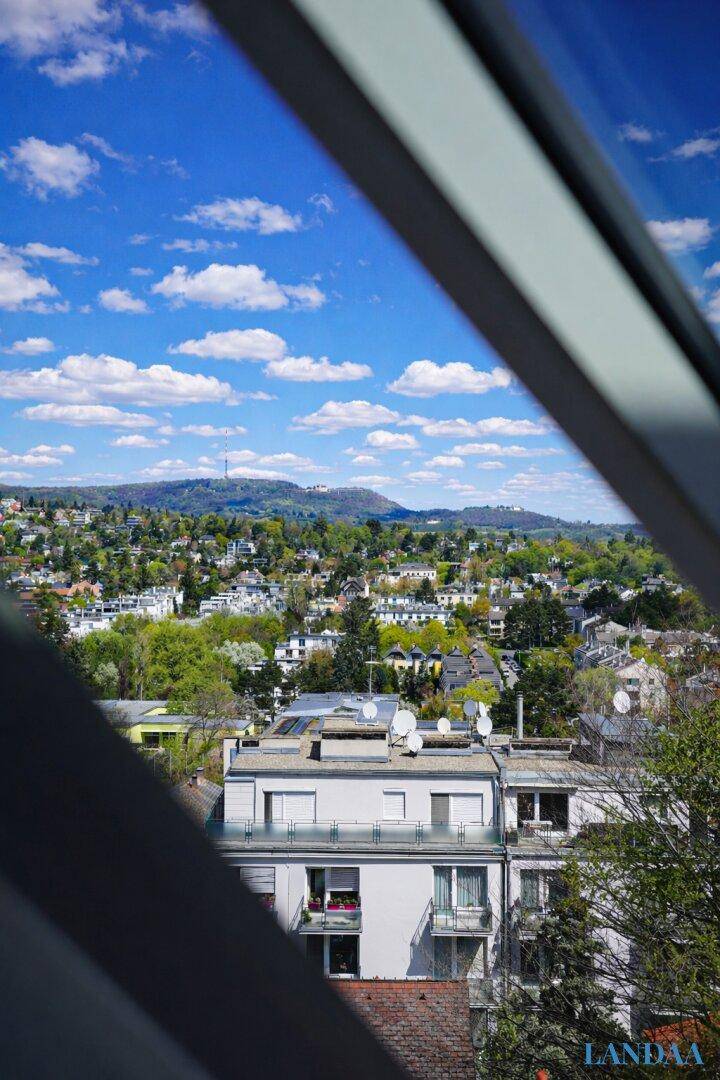 Blick aus dem Fenster auf die umliegende Wohngegend und grüne Landschaft.