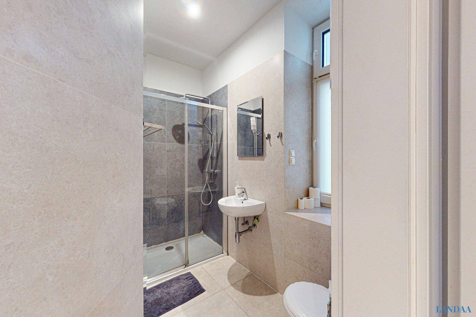 Modernes Badezimmer mit Duschkabine, Waschbecken und Fenster.