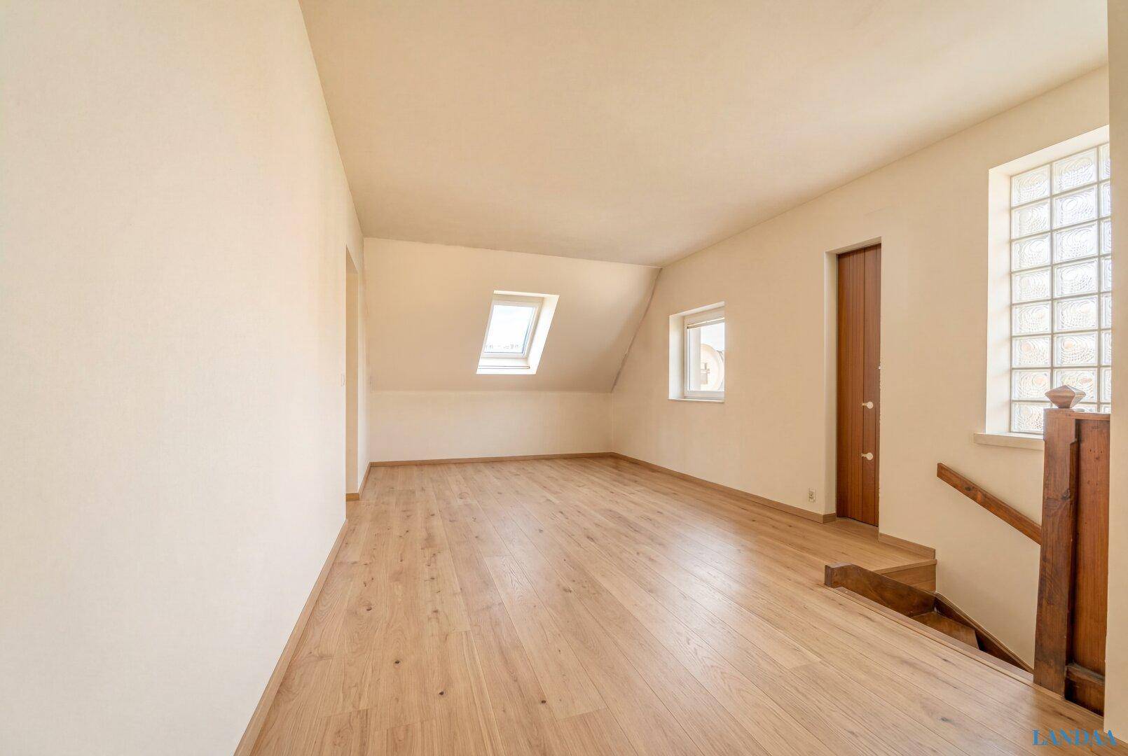 Helle Diele im Dachgeschoss mit Holzboden, Dachfenster und Zugang zu weiteren Räumen.