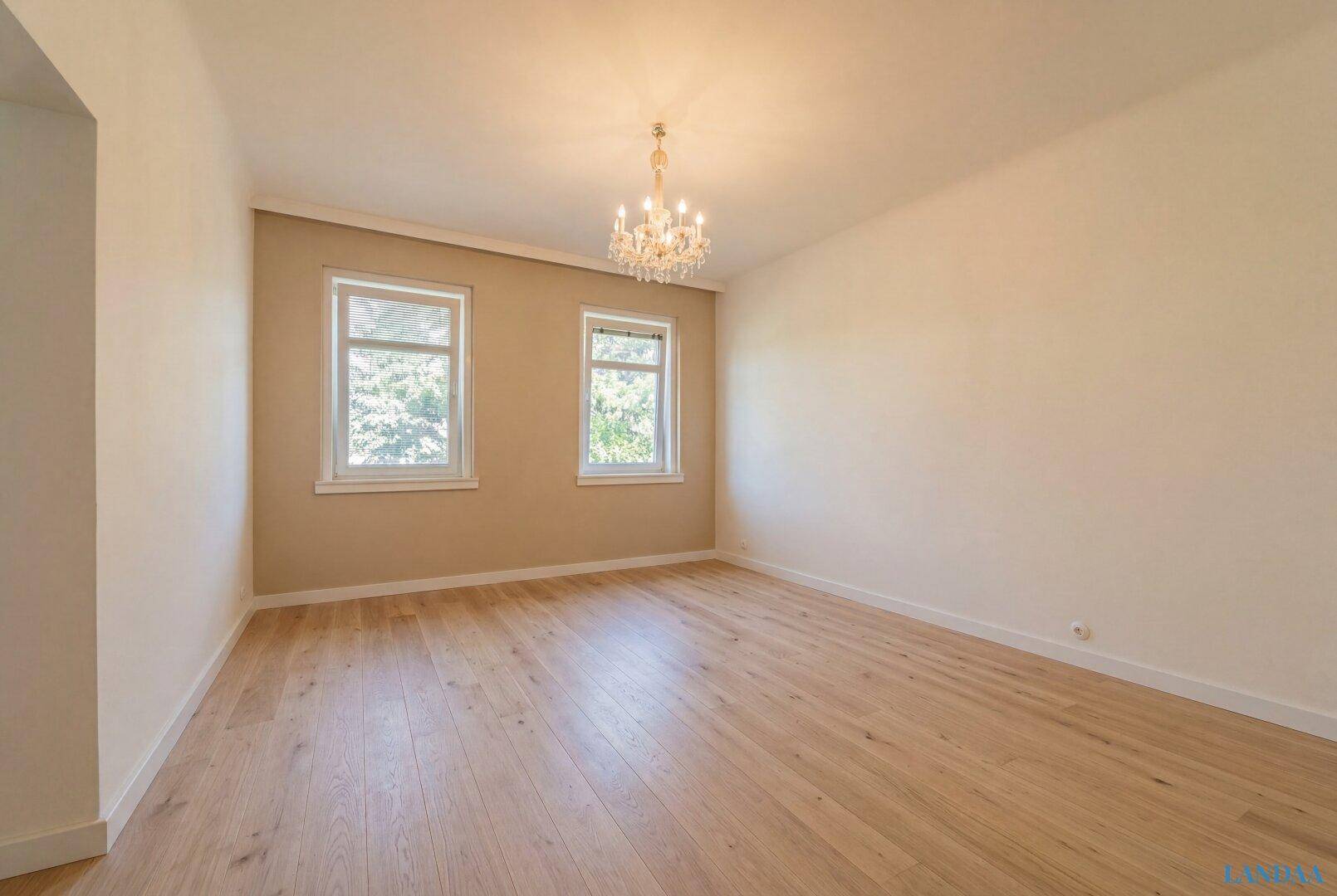 Geräumiger Raum mit Holzboden, hellen Wänden und elegantem Kronleuchter, vielseitig nutzbar.