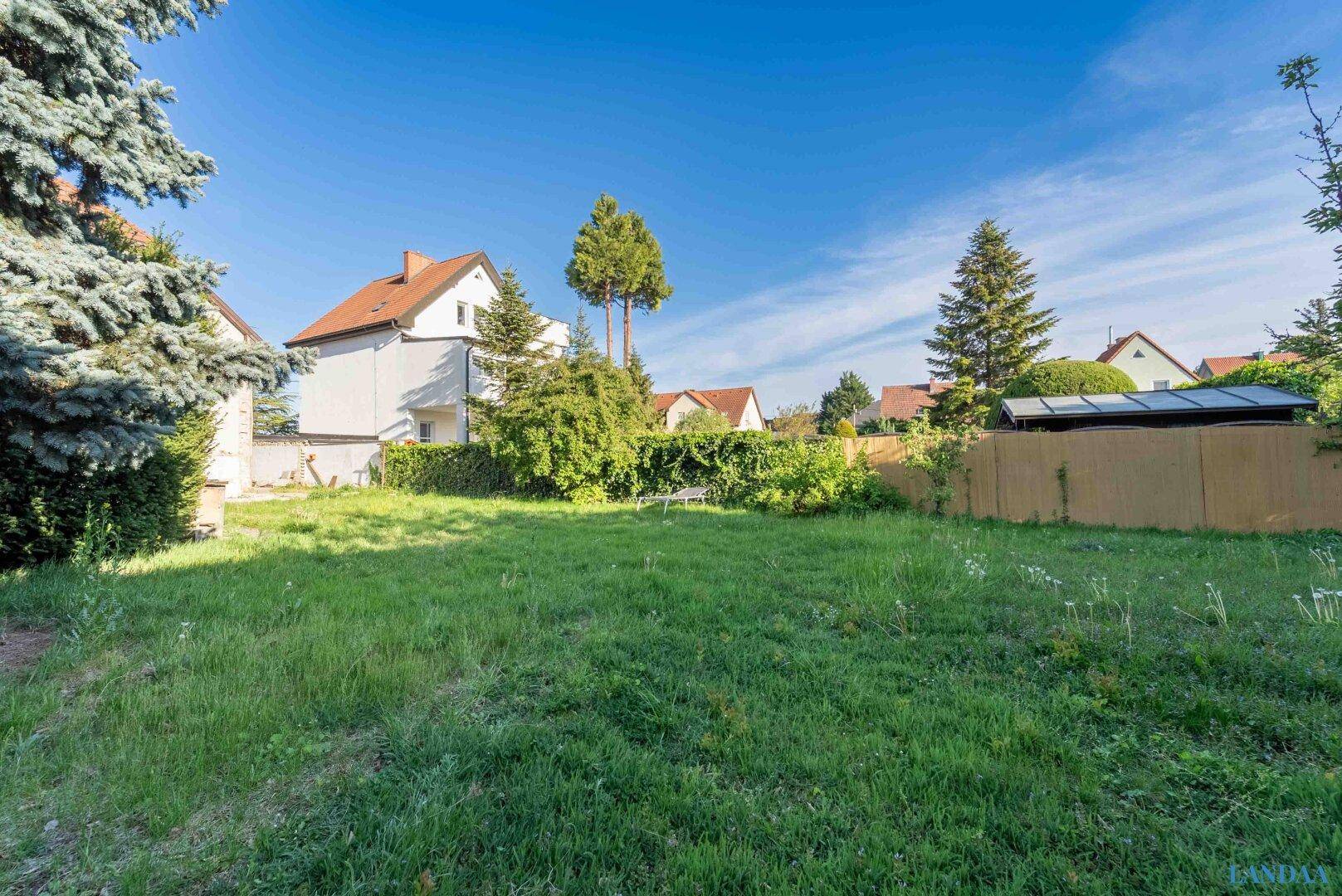 Großer Garten mit Rasenfläche und Bäumen, umgeben von weiteren Wohnhäusern in ruhiger Lage.
