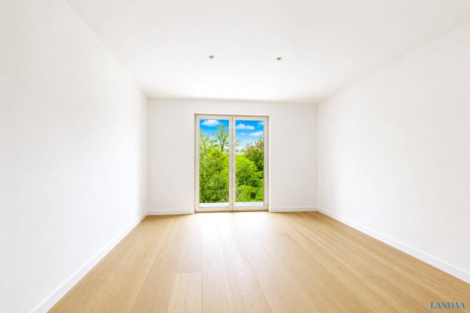 Helles Zimmer mit Holzboden und großem Fenster, das Zugang zu einem Außenbereich bietet.