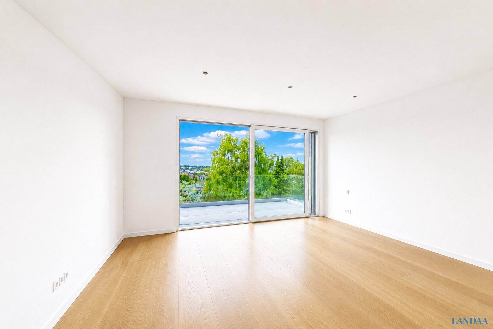 Lichtdurchflutetes Zimmer mit Schiebetür zu einer Terrasse und weitem Ausblick.