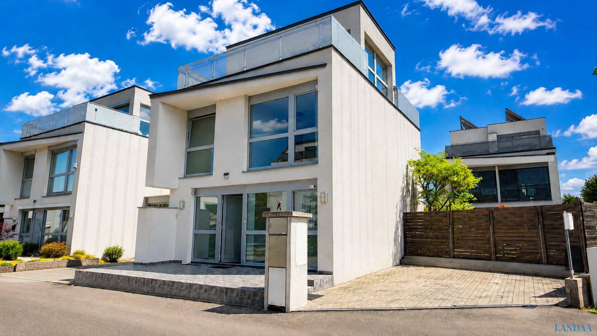 Moderne Architektur mit klaren Linien und großen Fenstern unter blauem Himmel.