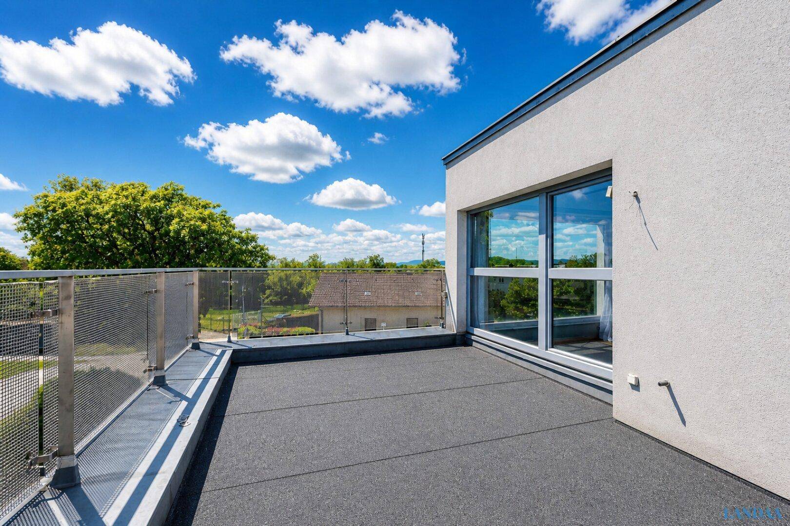 Weitläufige Dachterrasse mit Metallgeländer und Blick auf die Umgebung.